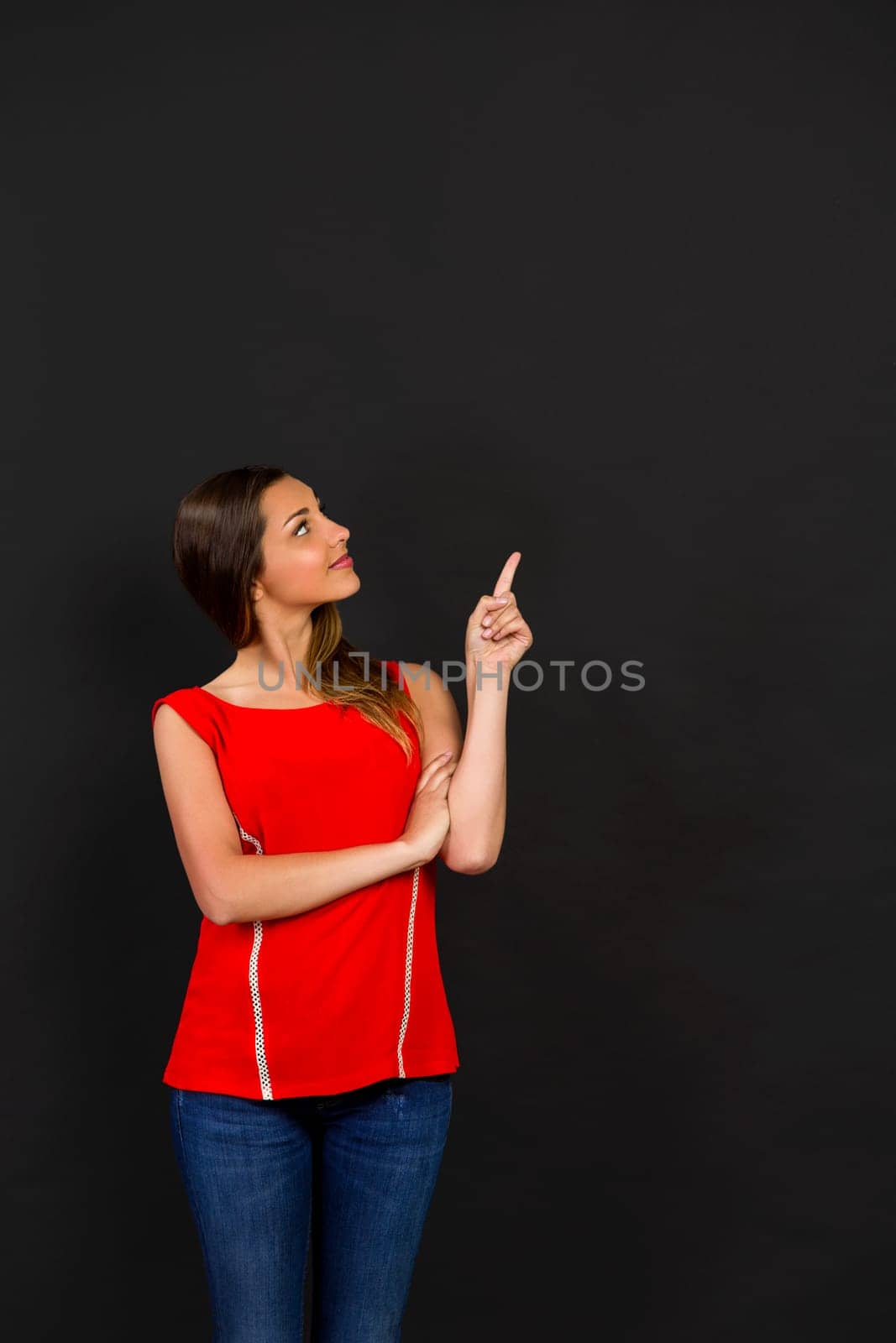Beautiful woman standing in front of a dark board and pointing