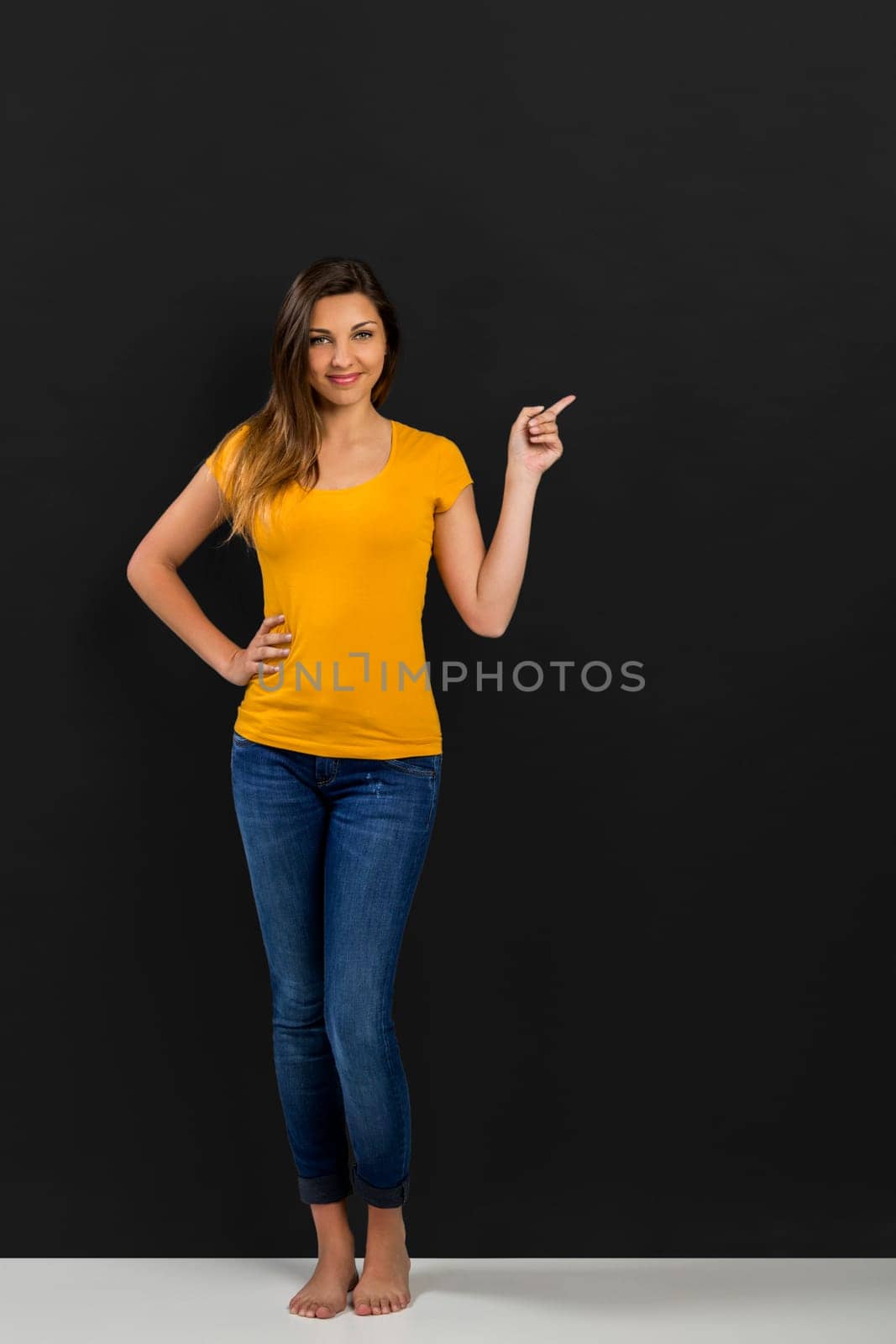 Beautiful woman standing in front of a dark board and pointing