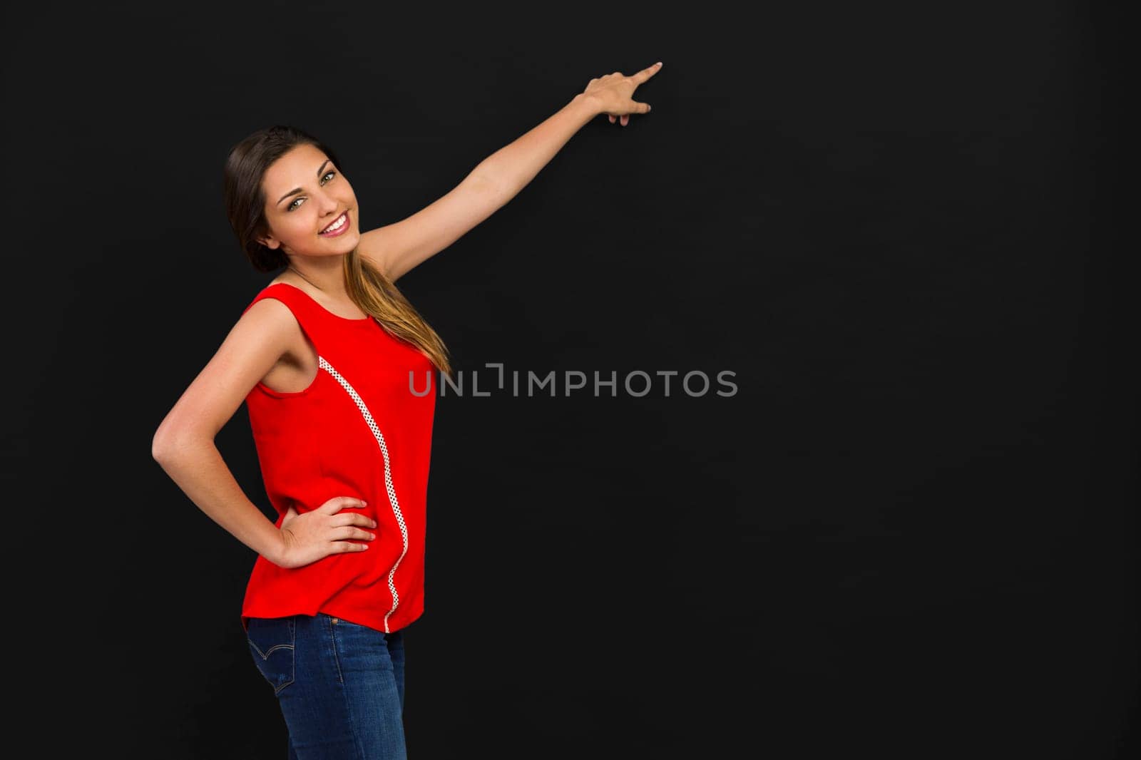 Beautiful woman standing in front of a dark board and pointing
