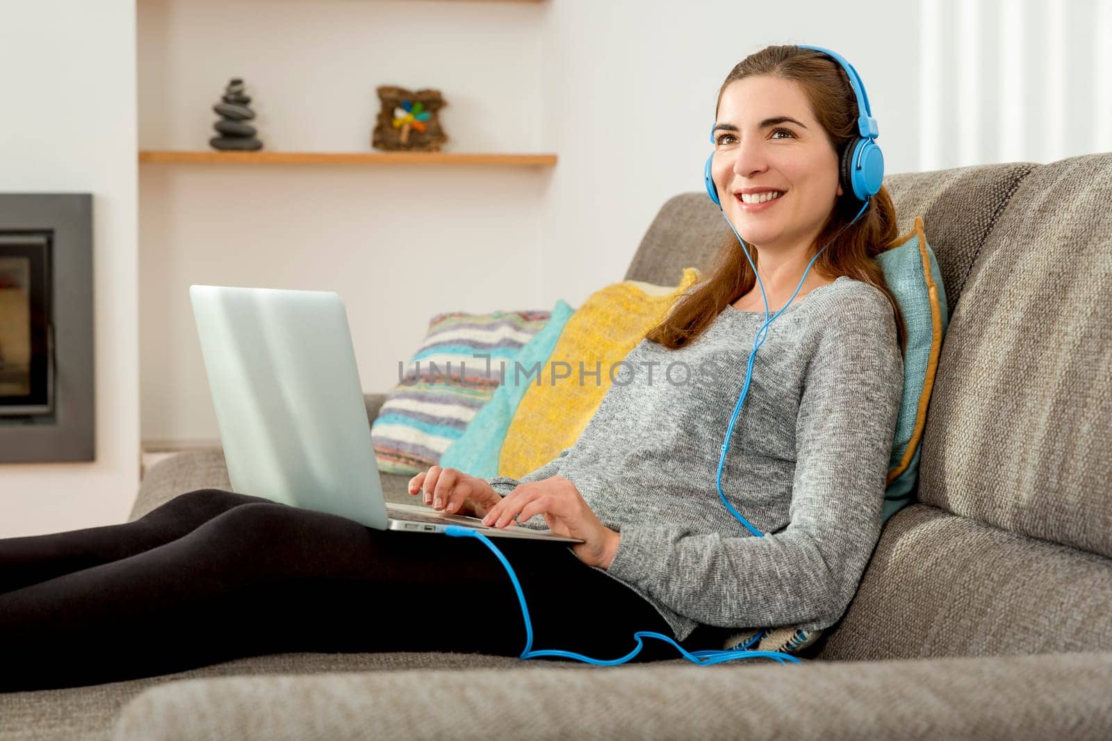 Beautiful woman working at home with a laptop while listen music and drinking coffee