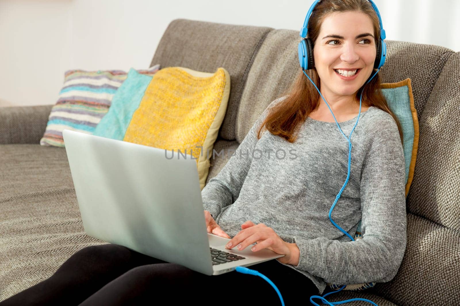 Beautiful woman working at home with a laptop while listen music and drinking coffee