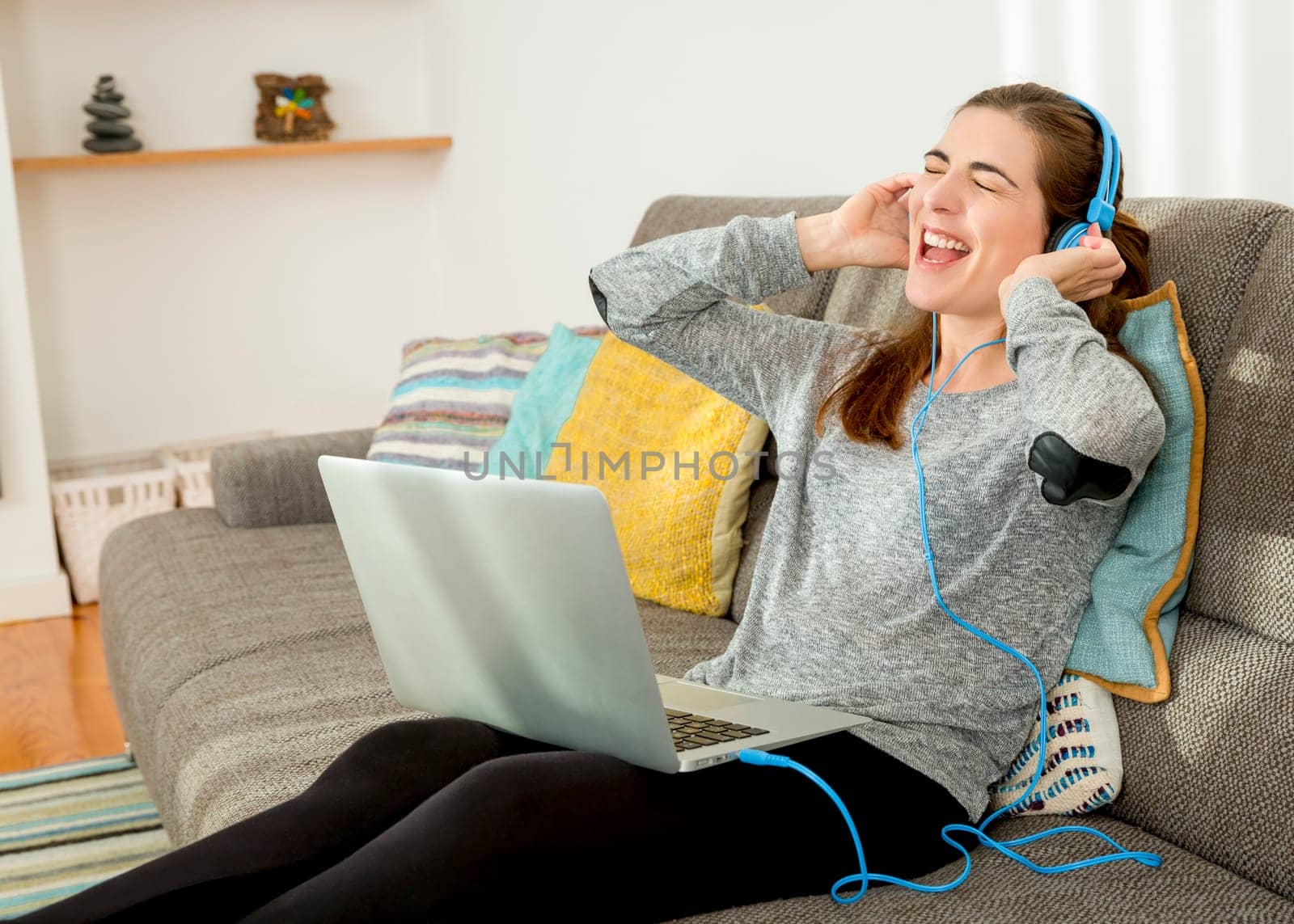 Beautiful woman working at home with a laptop while listen music and drinking coffee