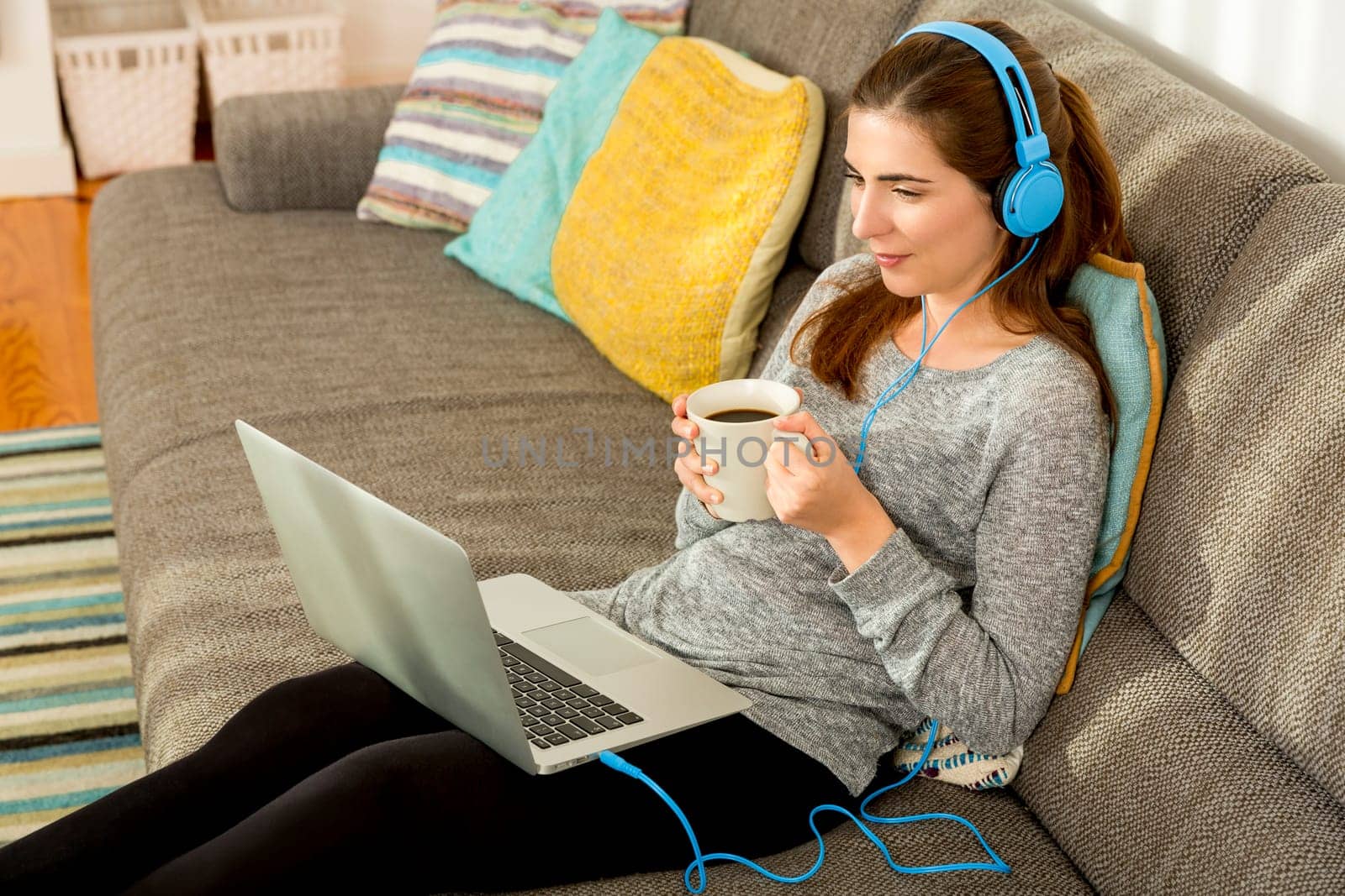 Beautiful woman working at home with a laptop while listen music and drinking coffee