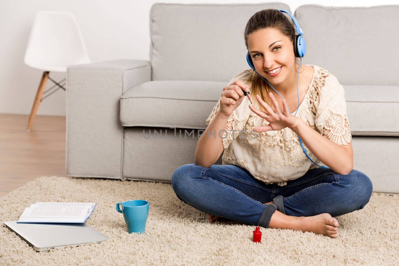 Beautiful woman at home making a pause to painting her nails while listening music