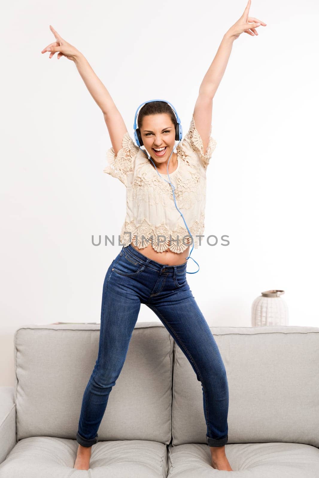 Beautiful woman at home listening music and dancing over the couch