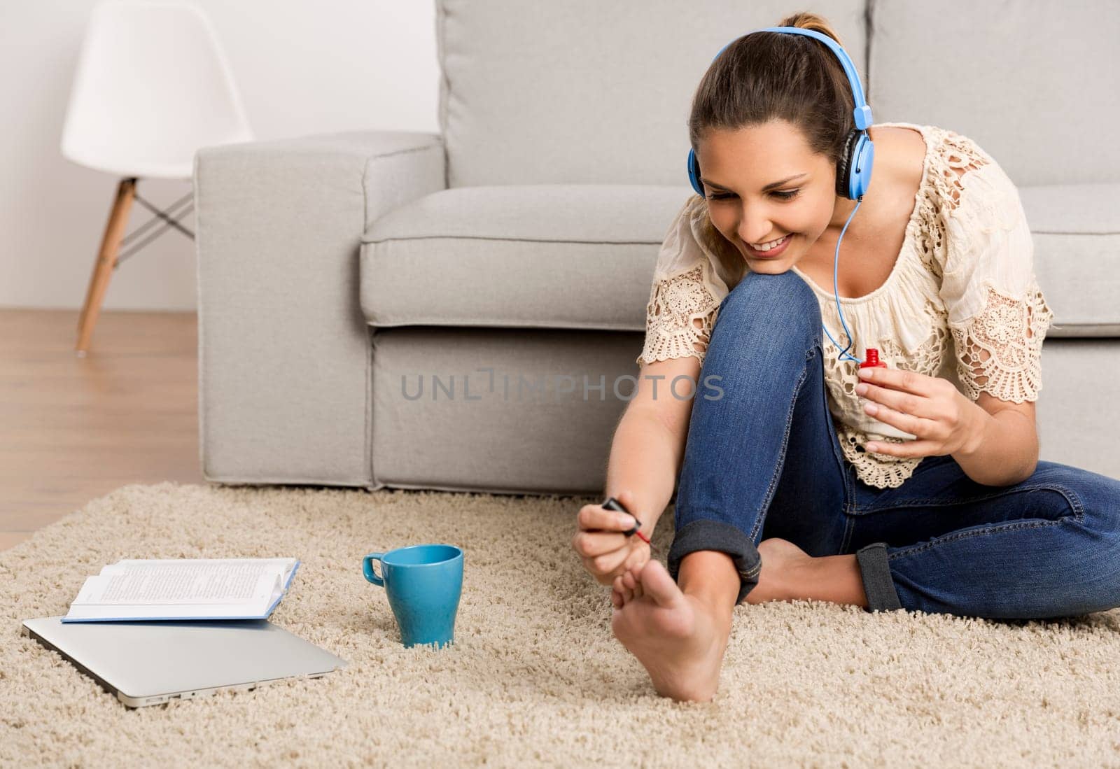 Beautiful woman at home making a pause to painting her nails while listening music