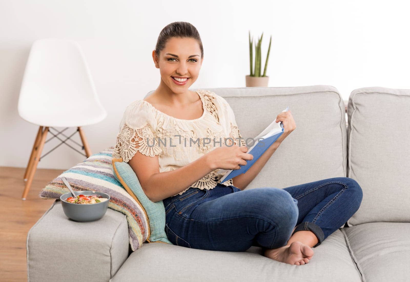 Beautiful woman at home sitting on the couch and reading a book
