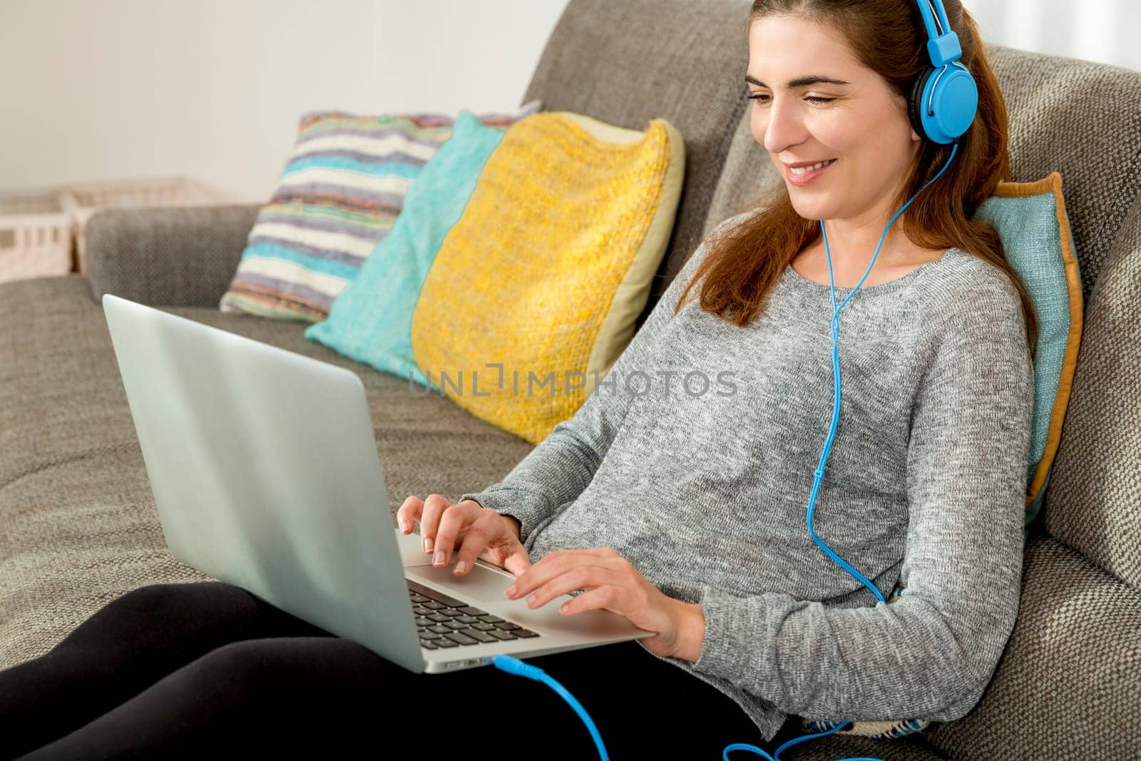 Beautiful woman working at home with a laptop while listen music and drinking coffee