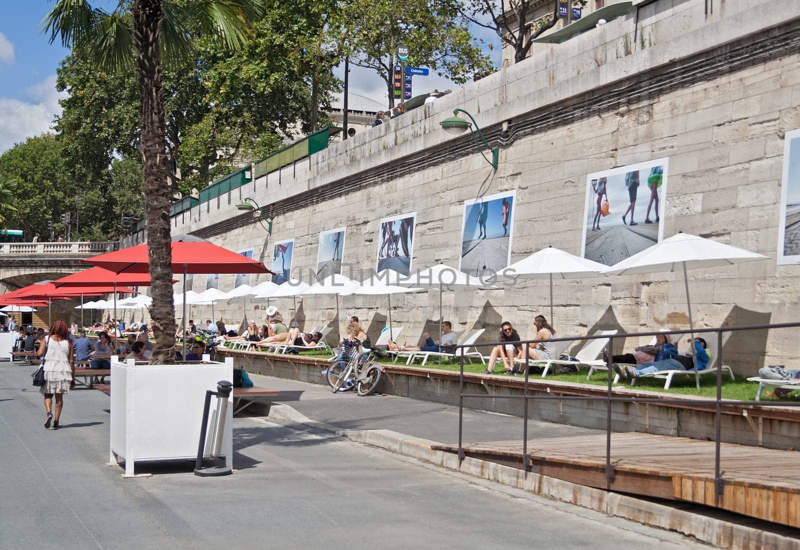 people lying in the sun on the banks of the seine in paris