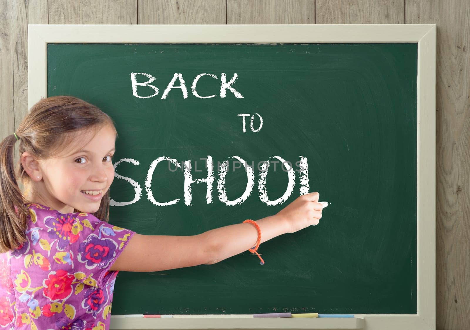 a pretty girl writting back to school on blackboard