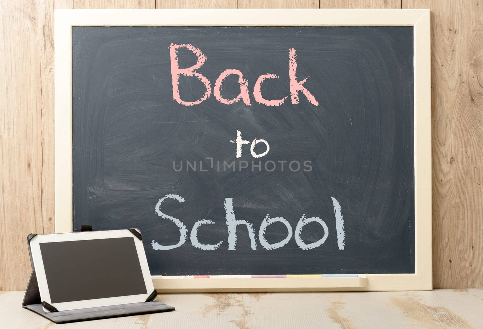 back to school written on blackboard with digital tablet