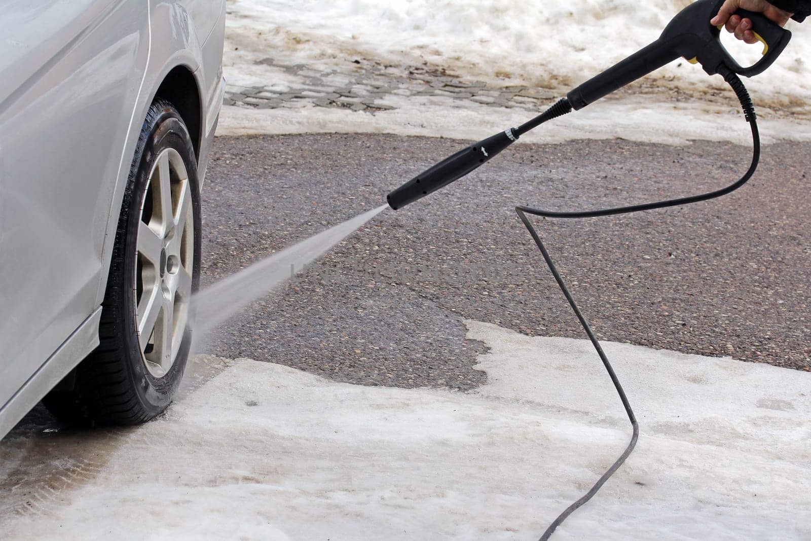 Car wash in winter - A man washes his car
