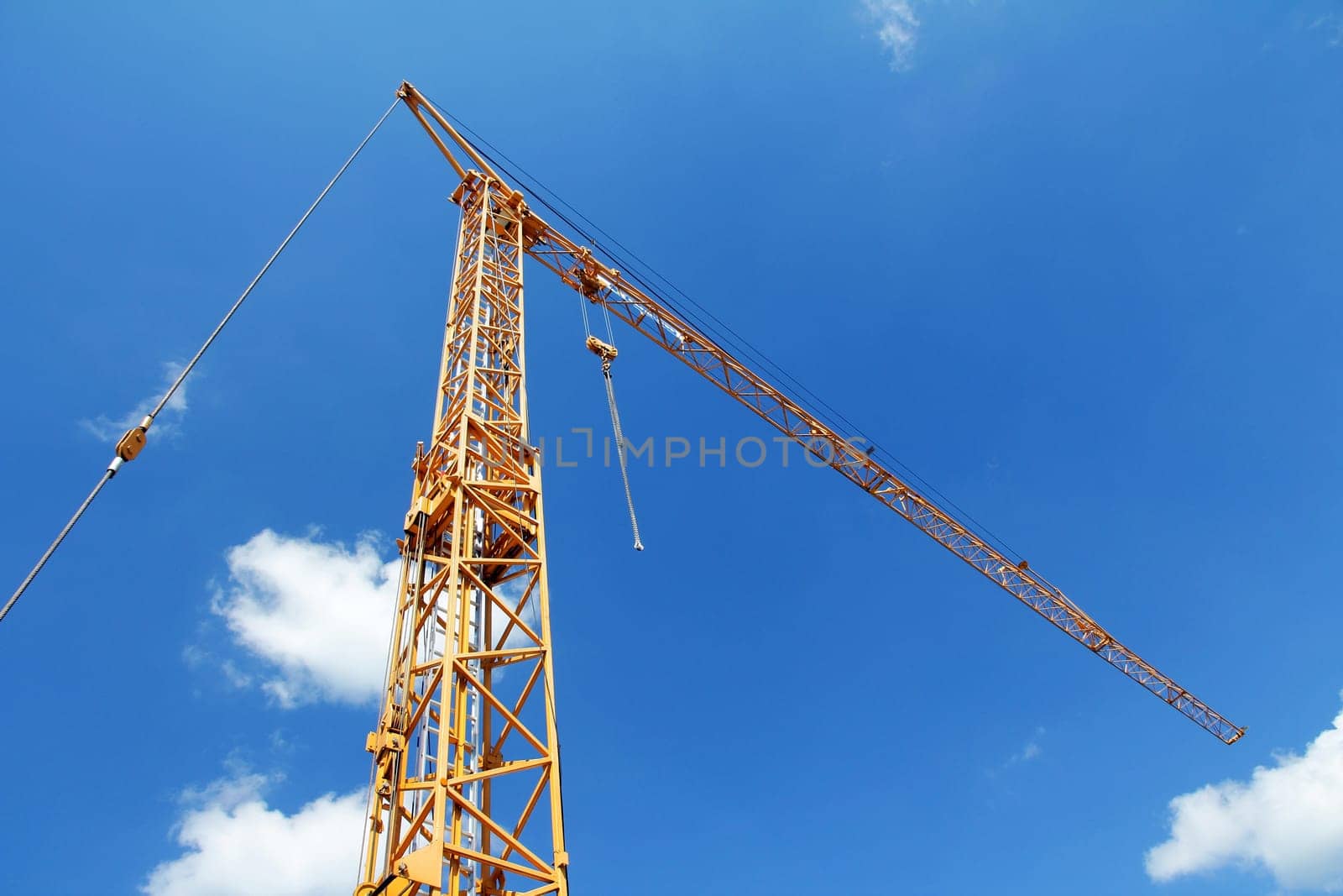 A yellow construction crane against the blue sky