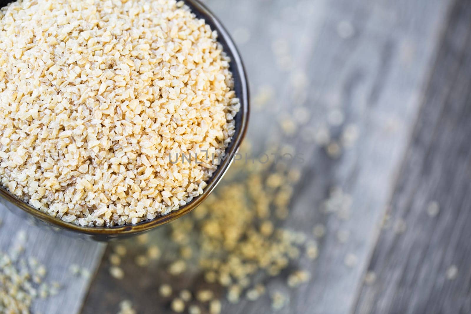 Bowl of dried bulgur wheat in rustic setting.