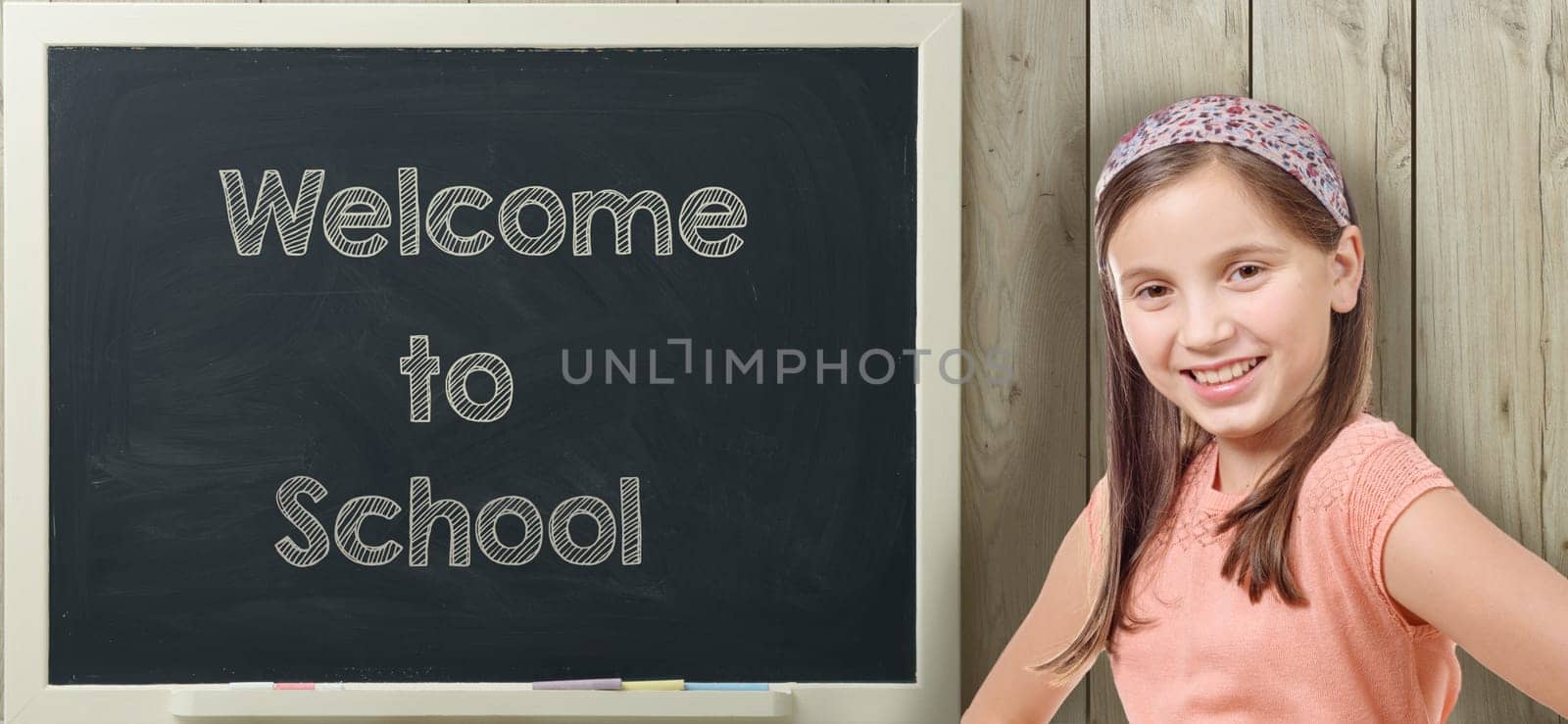 welcome to school written on  blackboard with pretty young girl