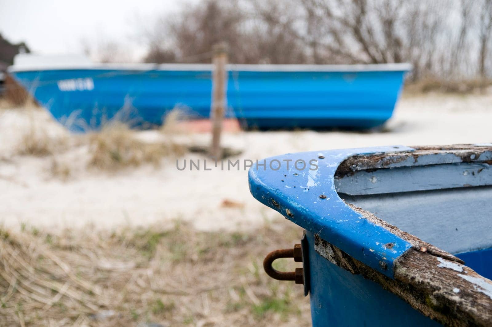 two blue rowing boats in the dunes on the Baltic Sea beach on the island of Usedom Front of a worn boat sharp in the foreground,second boat lies across in the blurred background between dry dune grass