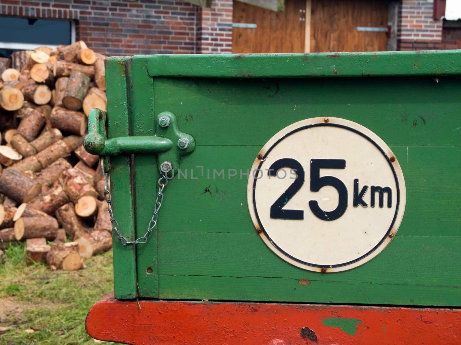 Close-up of the tailgate with locking of a green trailer with a round white sign and the inscription "25km"" as the maximum speed"