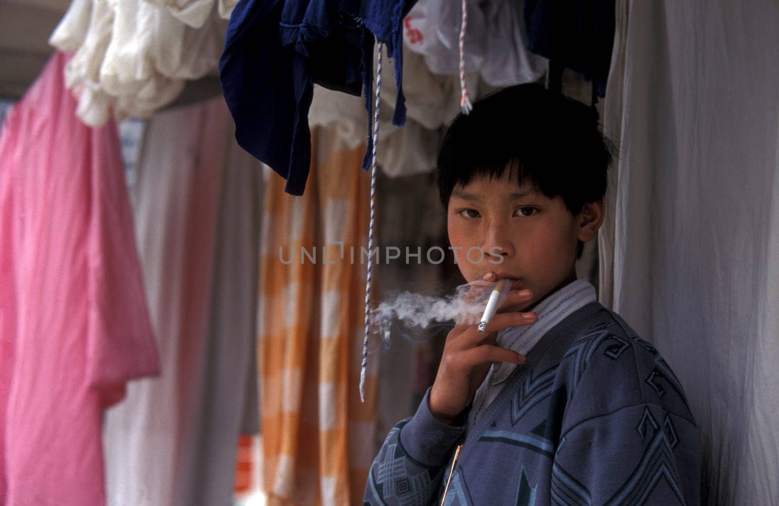 a boy is smoking cigarets at the yangzee river in the three gorges valley up of the three gorges dam project in the province of hubei in china.