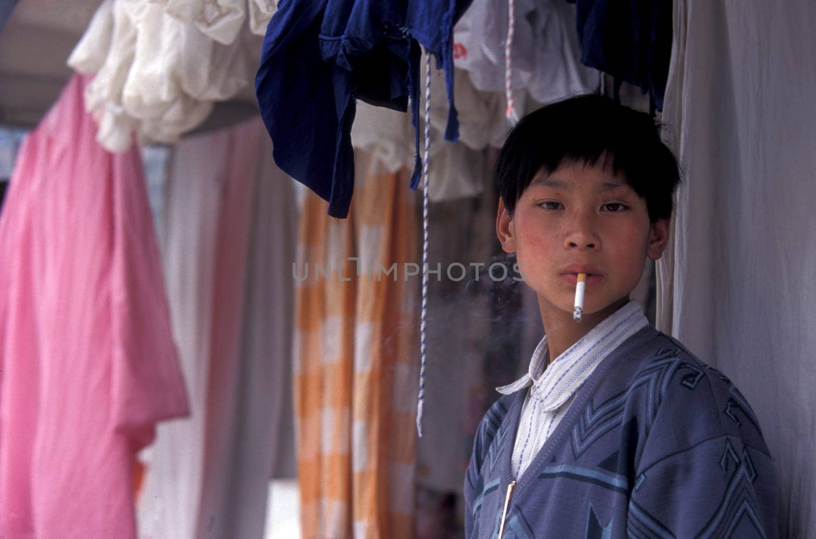 a boy is smoking cigarets at the yangzee river in the three gorges valley up of the three gorges dam project in the province of hubei in china.