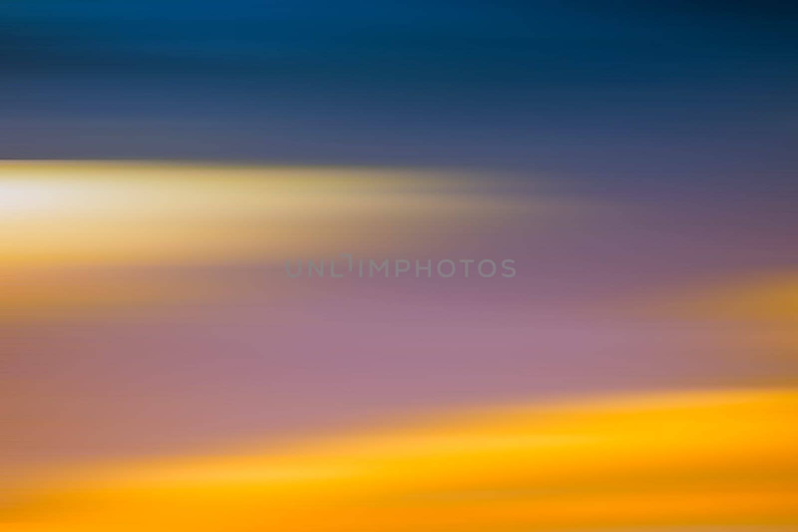 A blurred sky with different colored and colorful clouds.