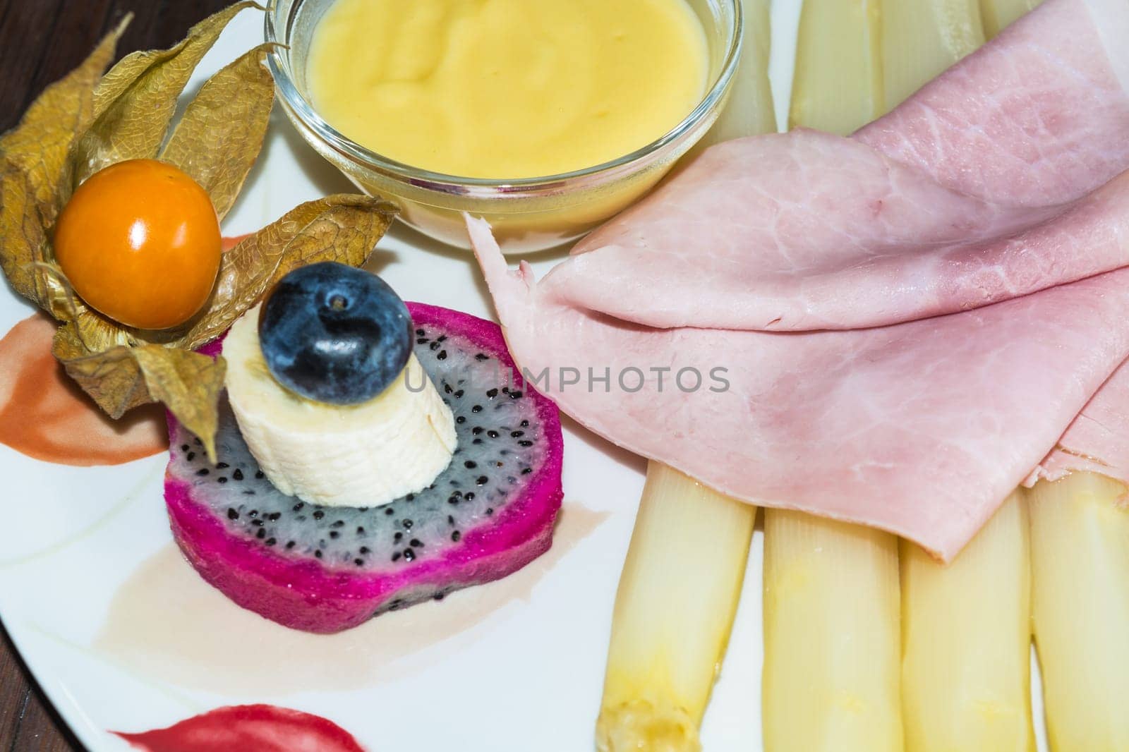 Simple asparagus dish with cooked ham and sauce garnned on a white plate. .