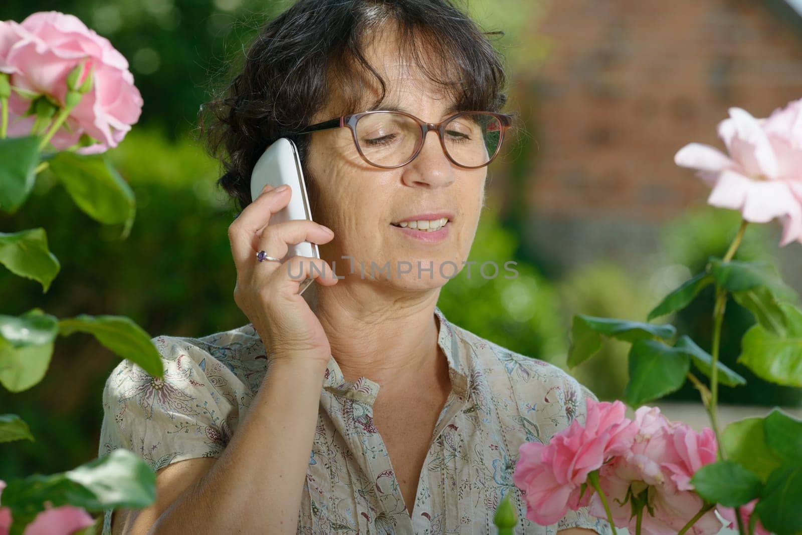 portrait of a mature woman with a phone in her garden