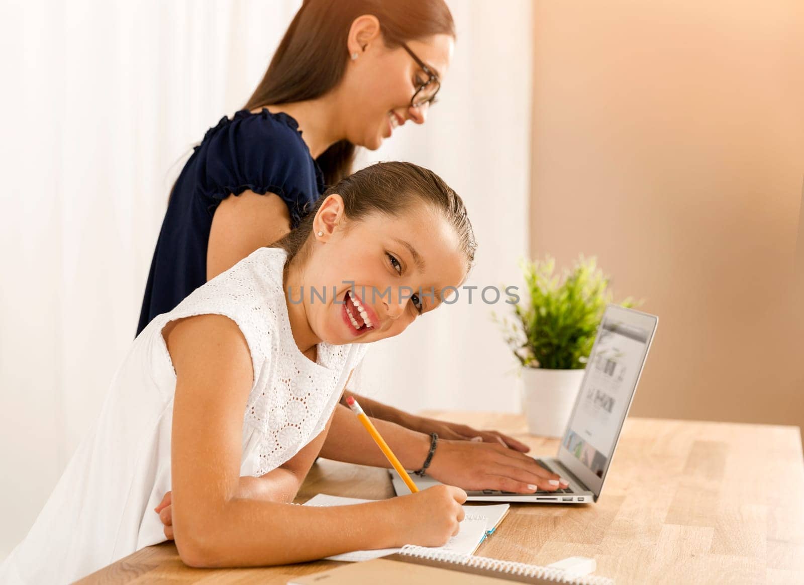 Mother helping her little daughter how to use a computer