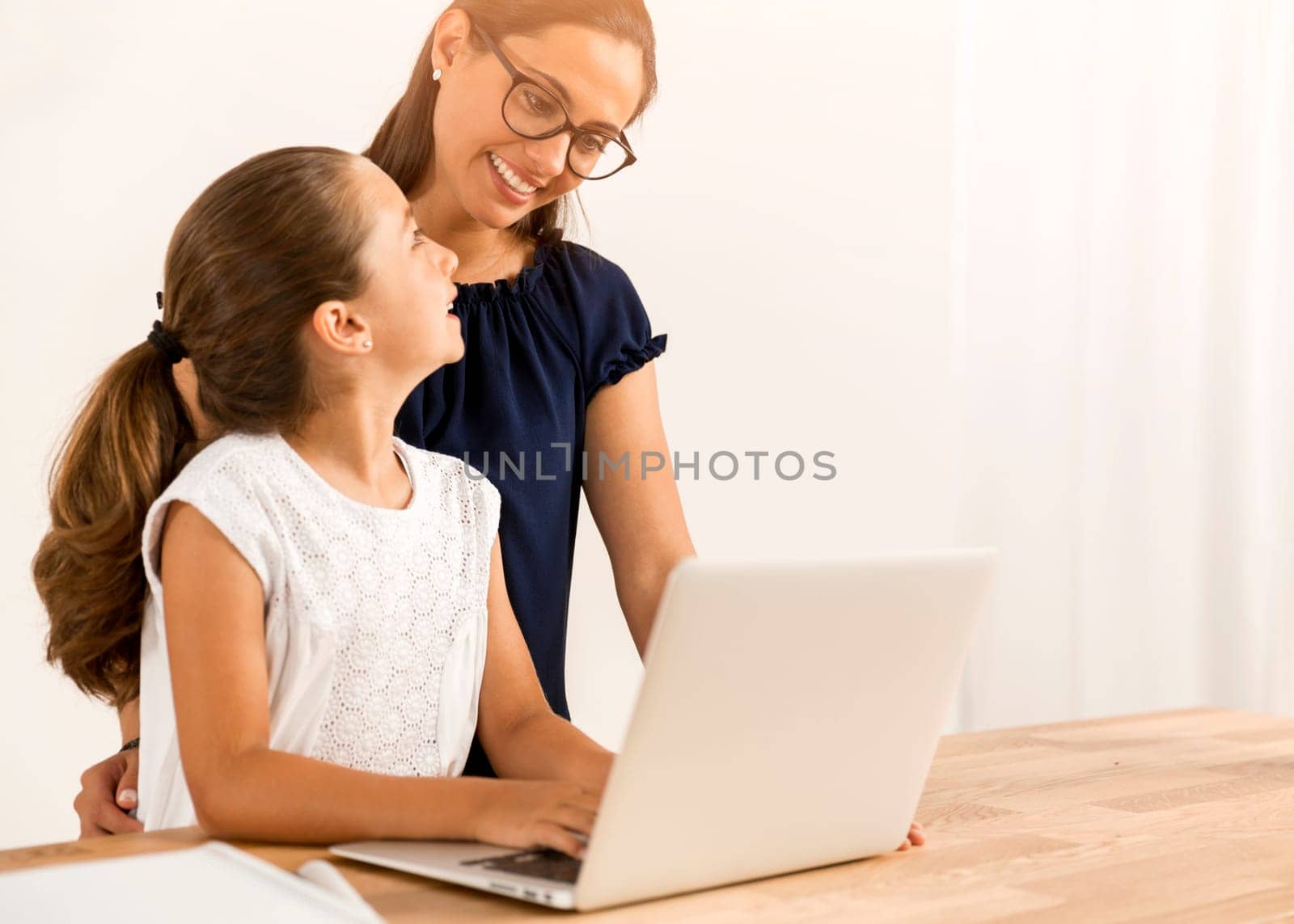 Mother helping her little daughter how to use a computer