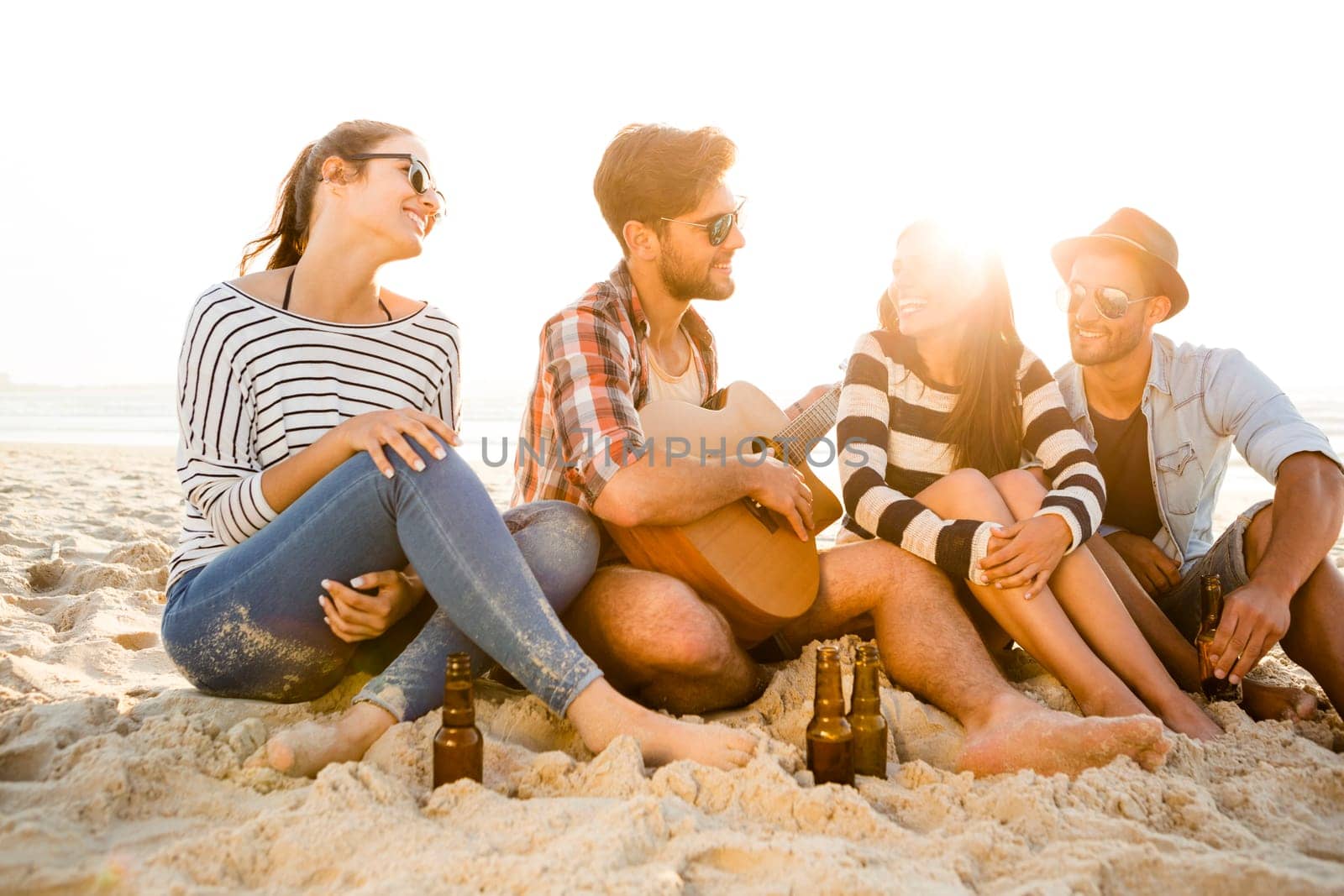 Friends having fun together at the beach and drinking a cold beer