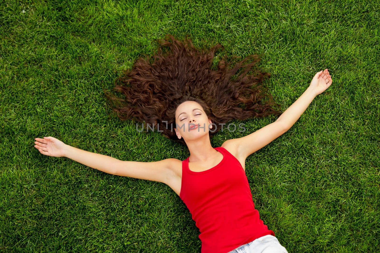 Outdoor portrait of a beautiful young woman lying on the grass