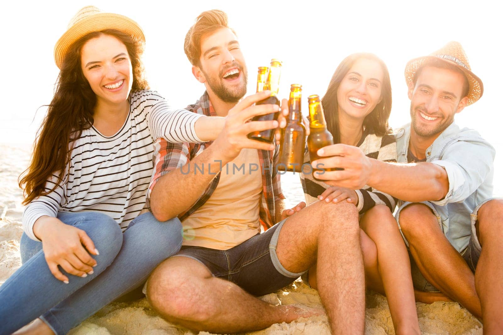 Friends having fun together at the beach and drinking a cold beer