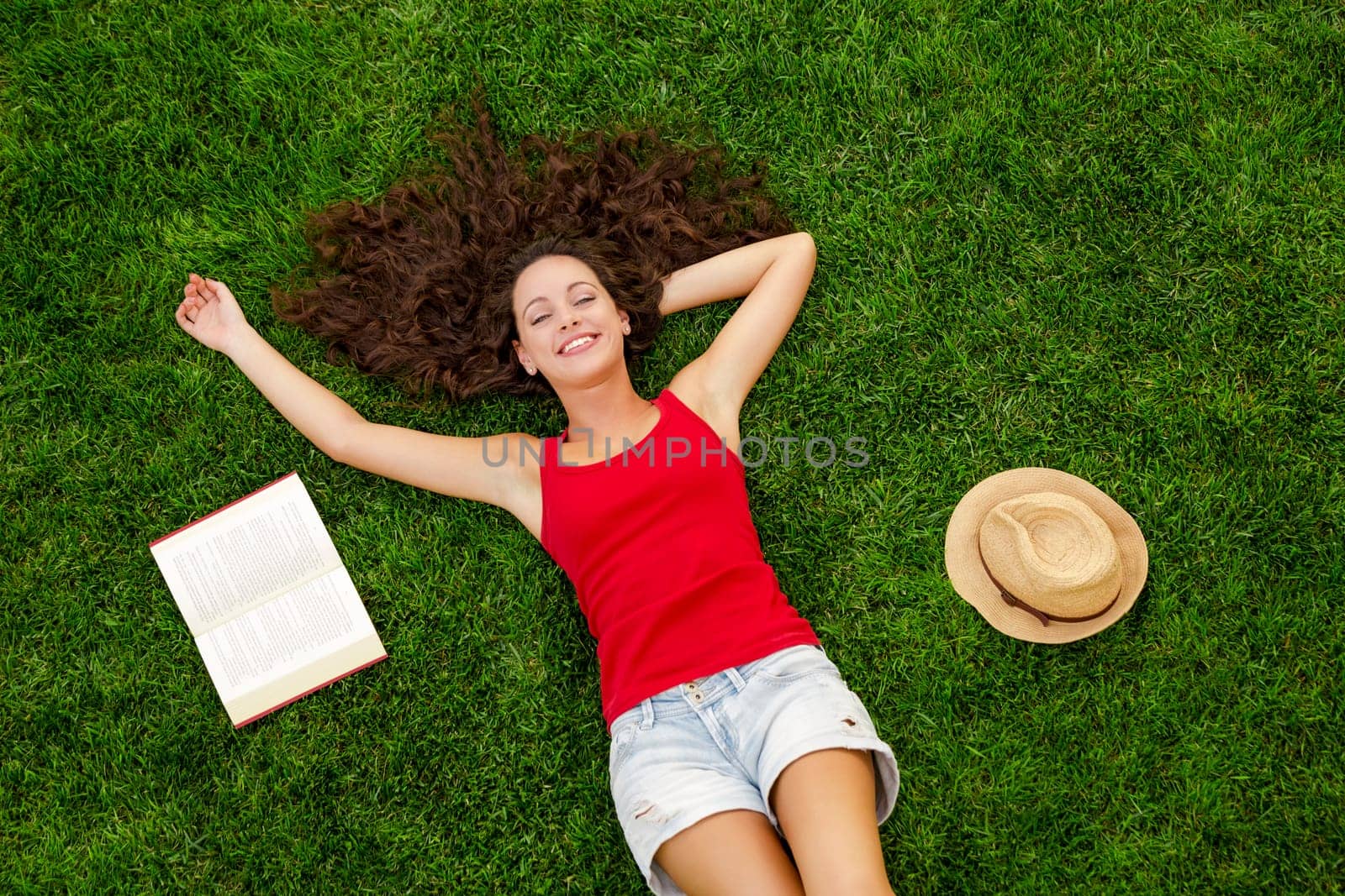 Happy young woman sitting on a blanket with arms stretched