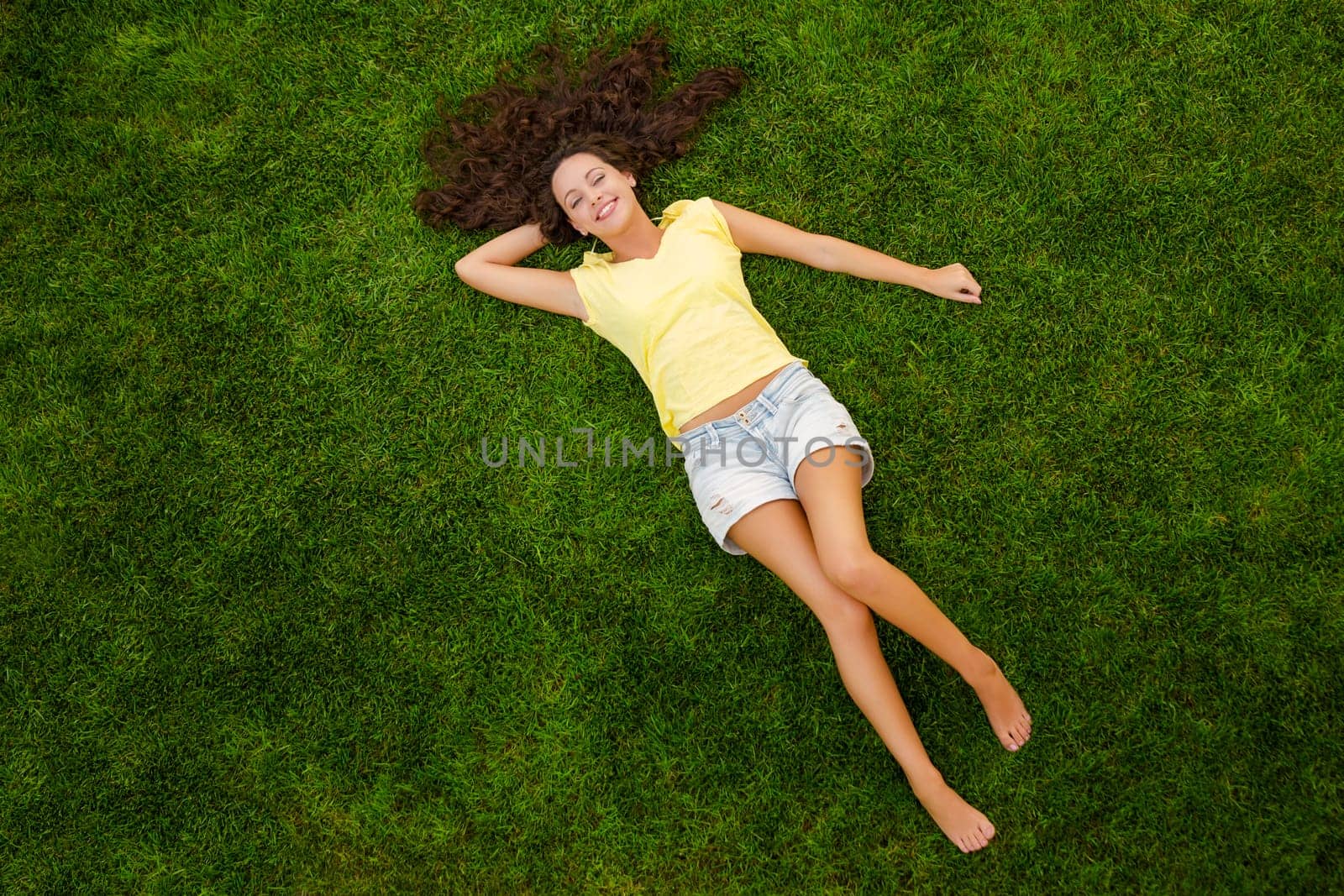 Outdoor portrait of a beautiful young woman lying on the grass