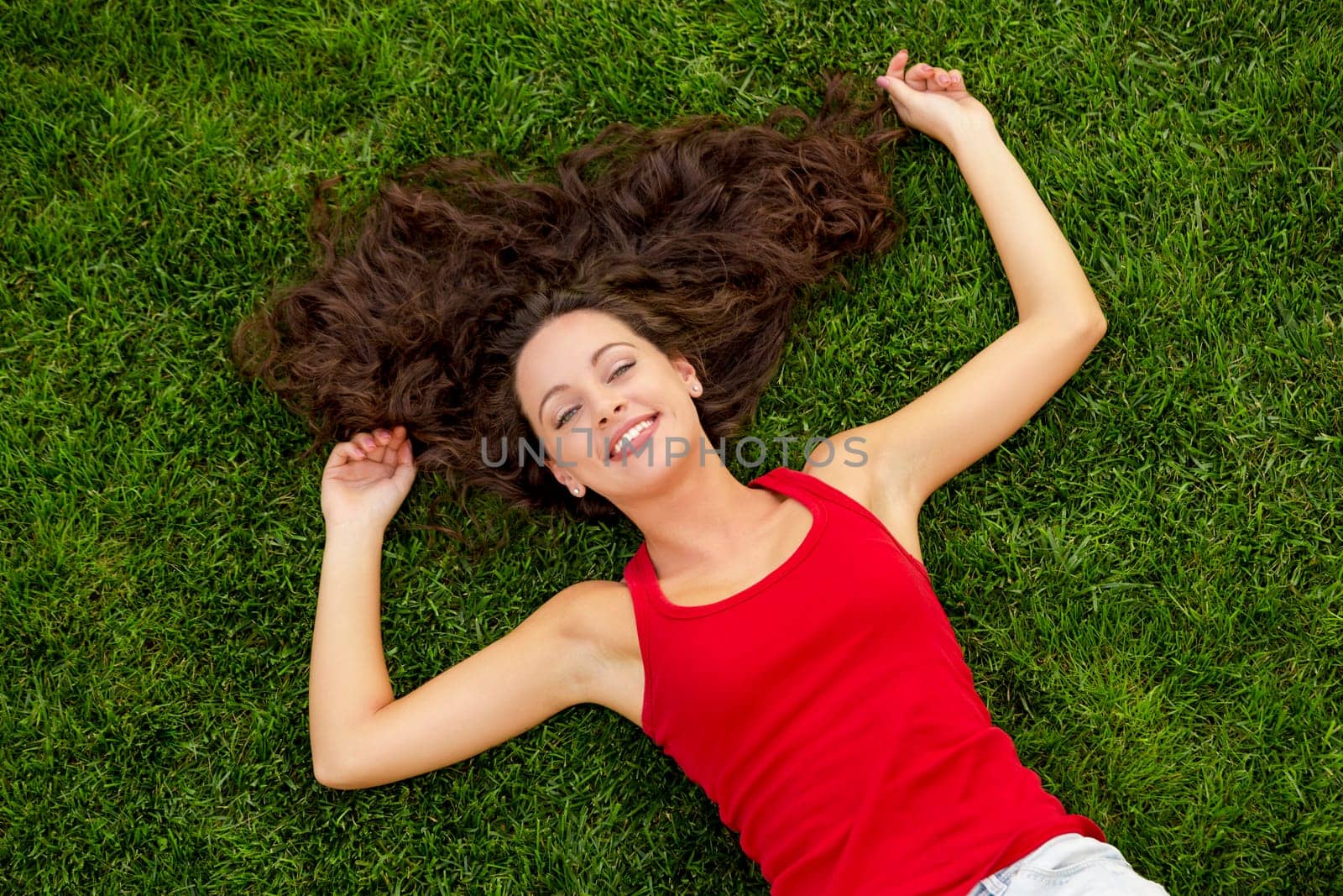 Outdoor portrait of a beautiful young woman lying on the grass