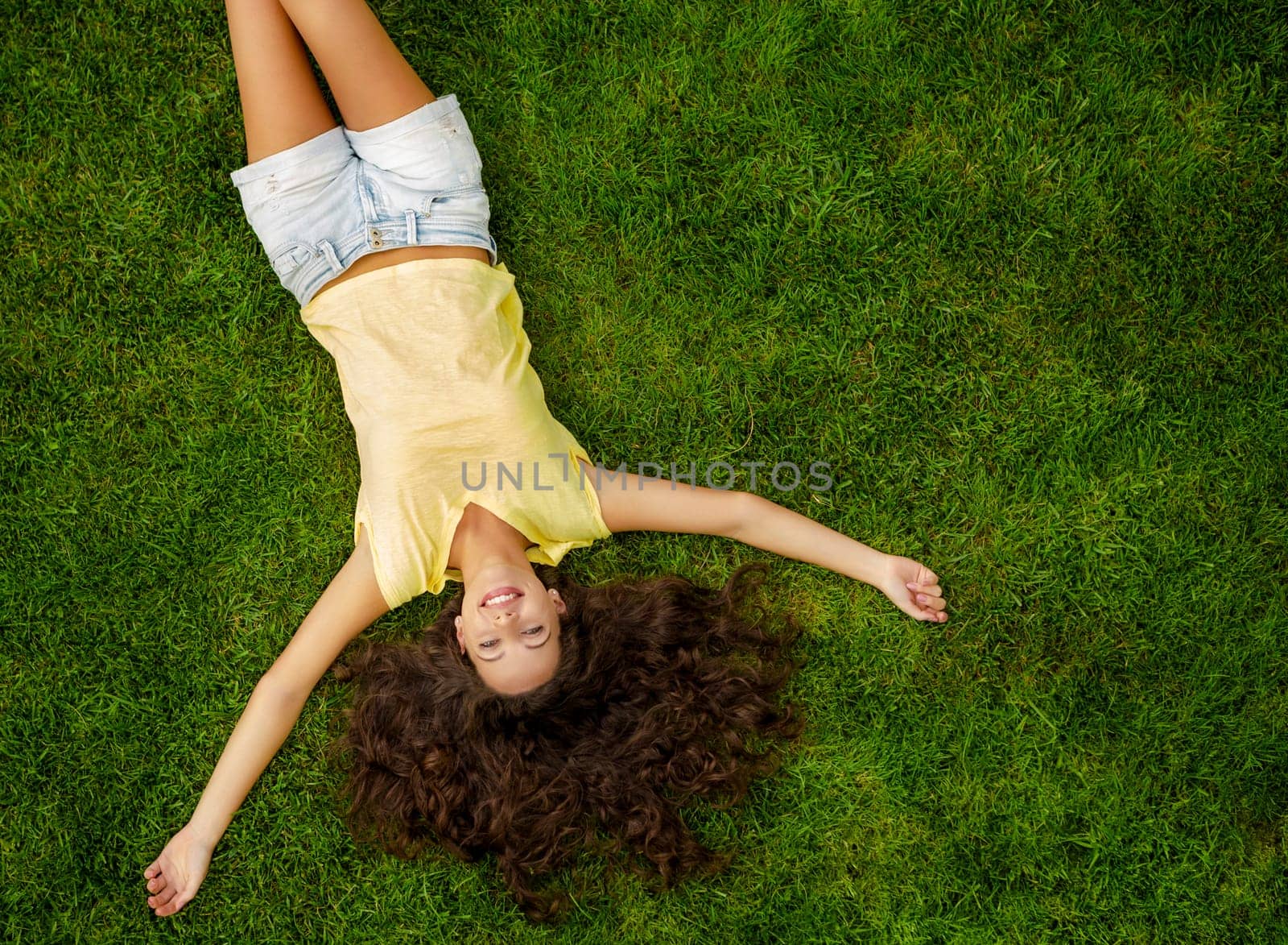 Portrait of a beautiful and happy young woman lying on the grass