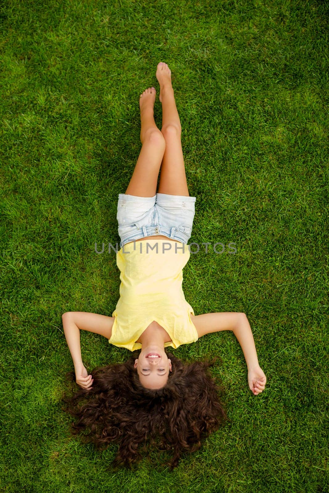 Portrait of a beautiful and happy young woman lying on the grass