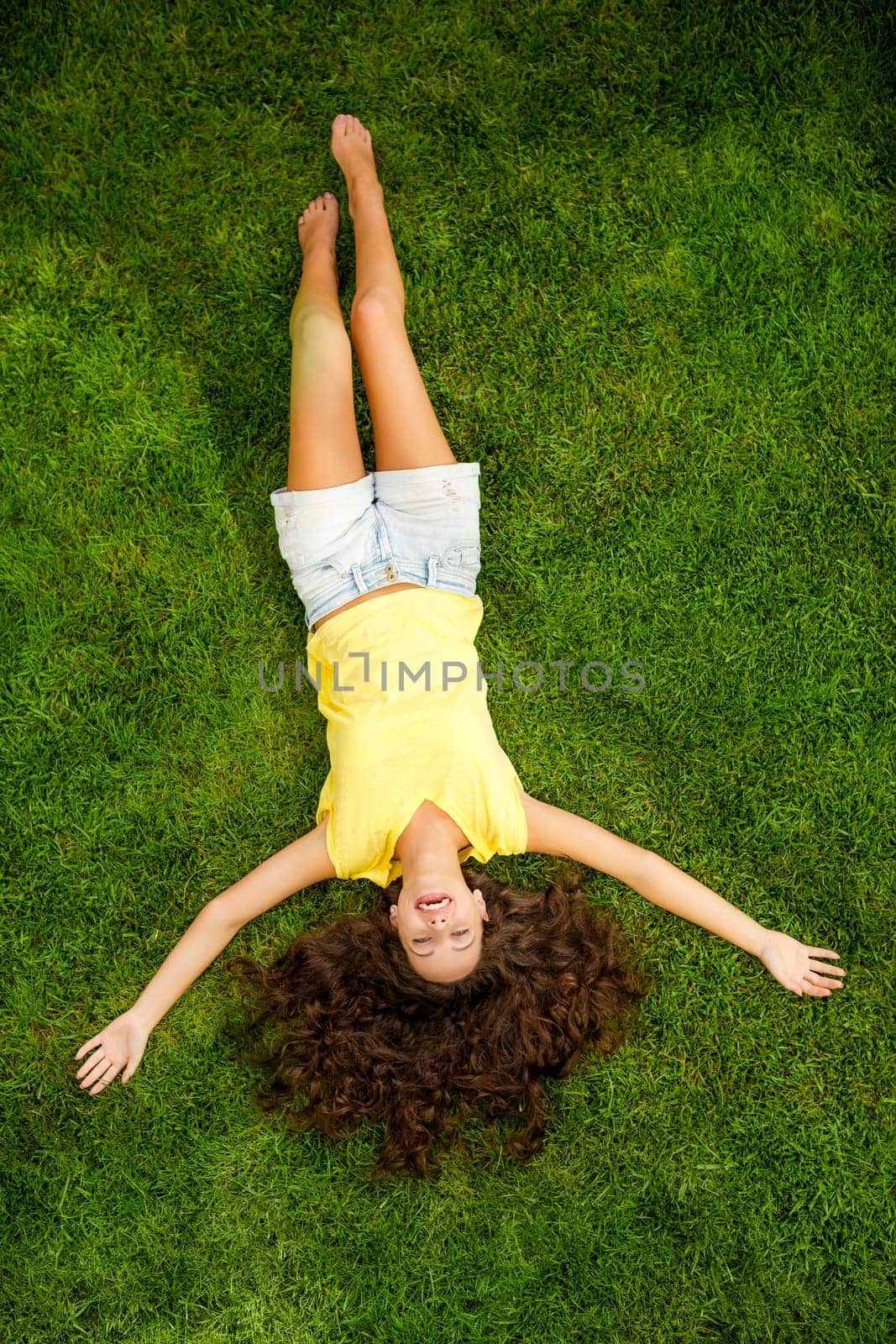 Portrait of a beautiful and happy young woman lying on the grass