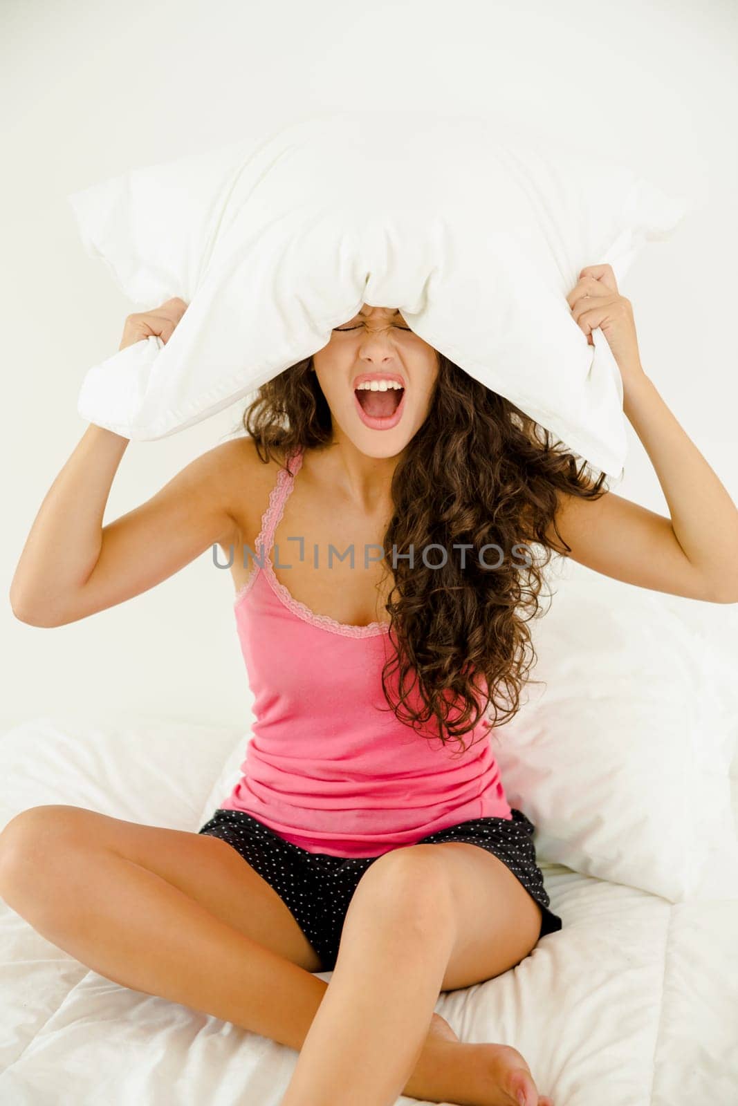 Woman in the bedroom holding a pillow and screaming