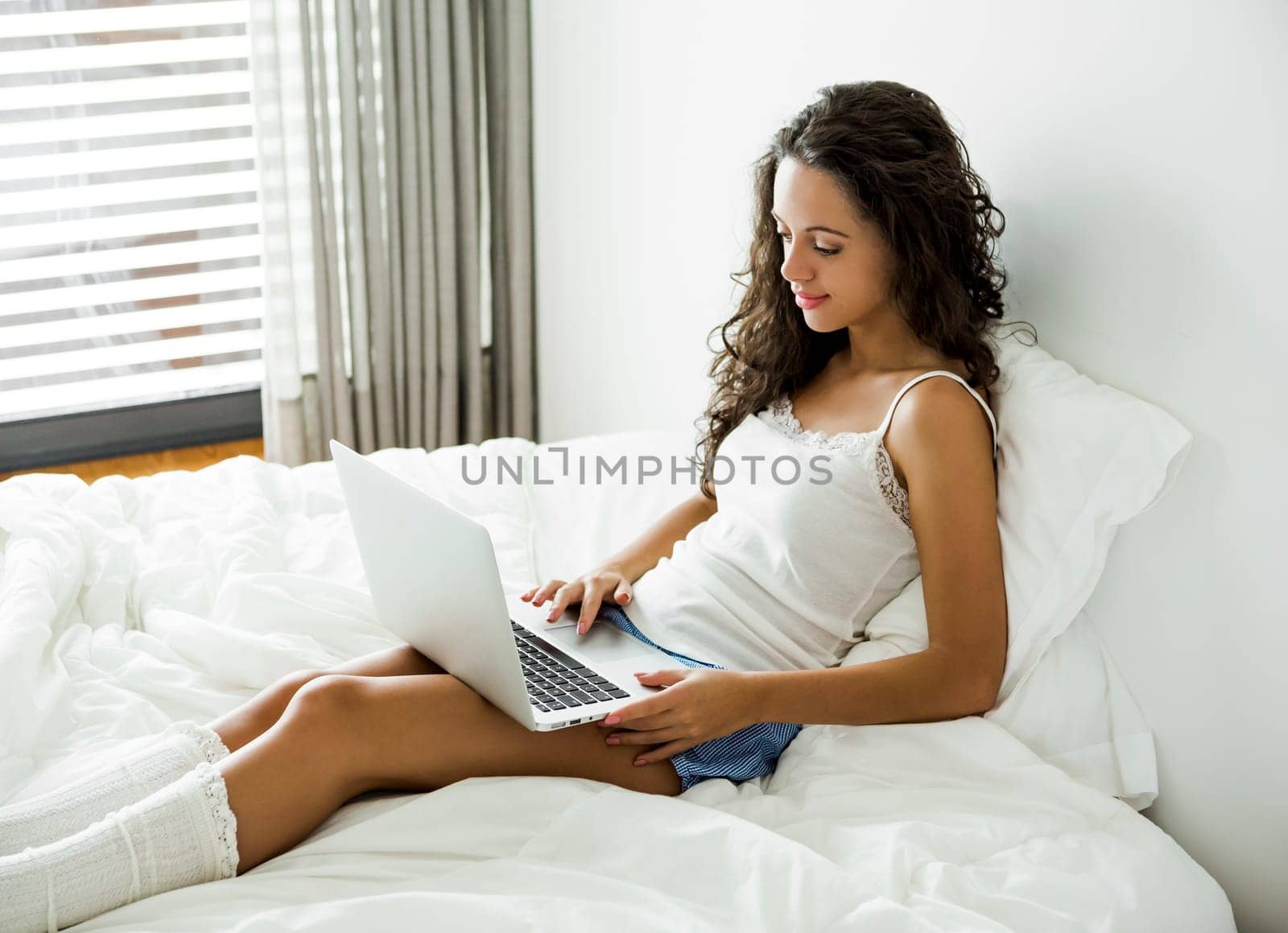 Beautiful woman working with a laptop on the bed