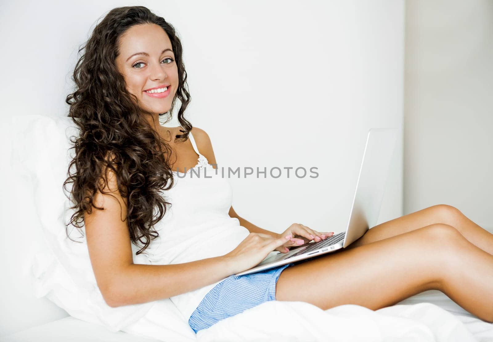 Beautiful woman working with a laptop on the bed