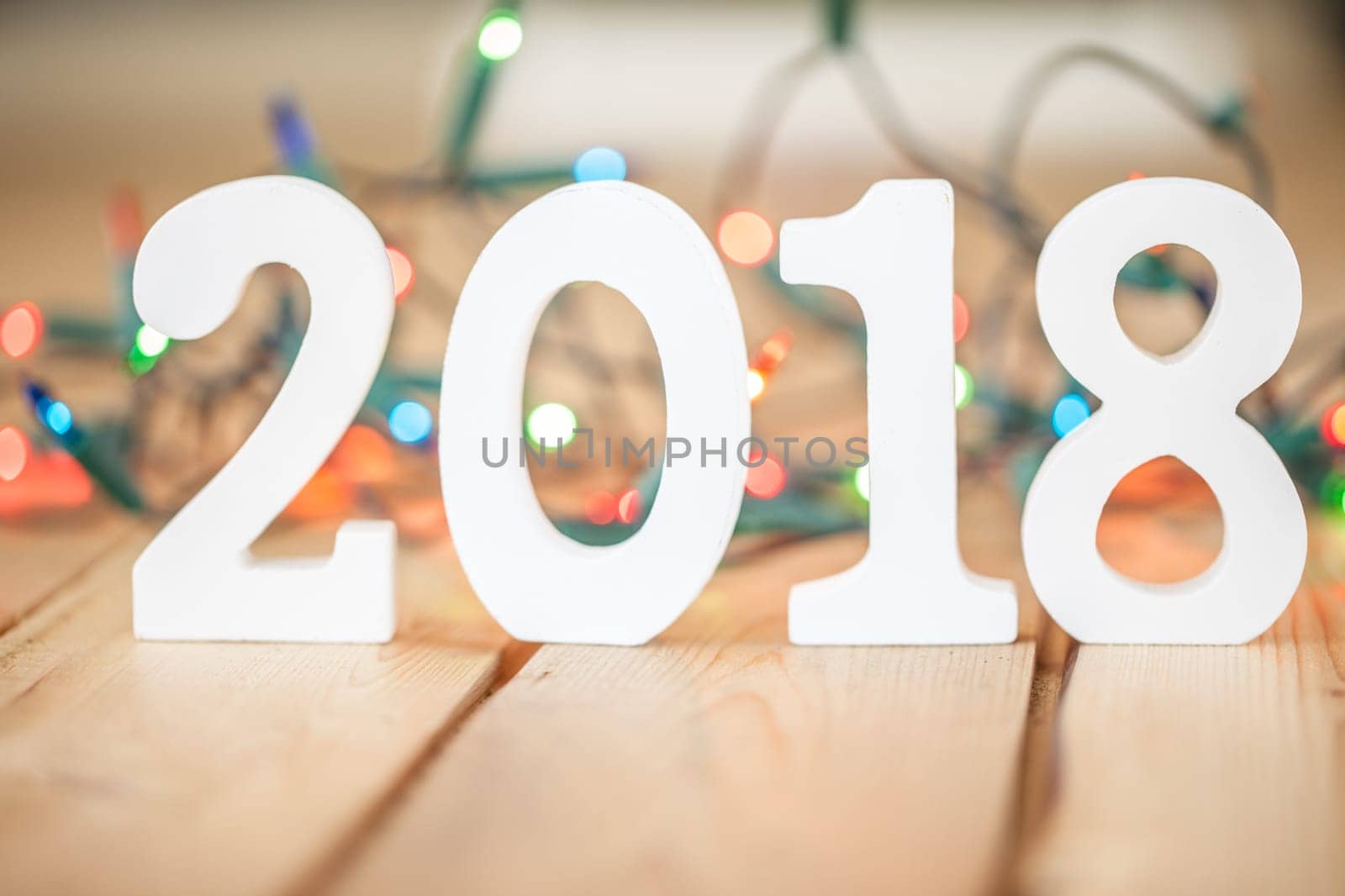 Numbers made of wood 2018 in front of colorful string of lights,selective focus