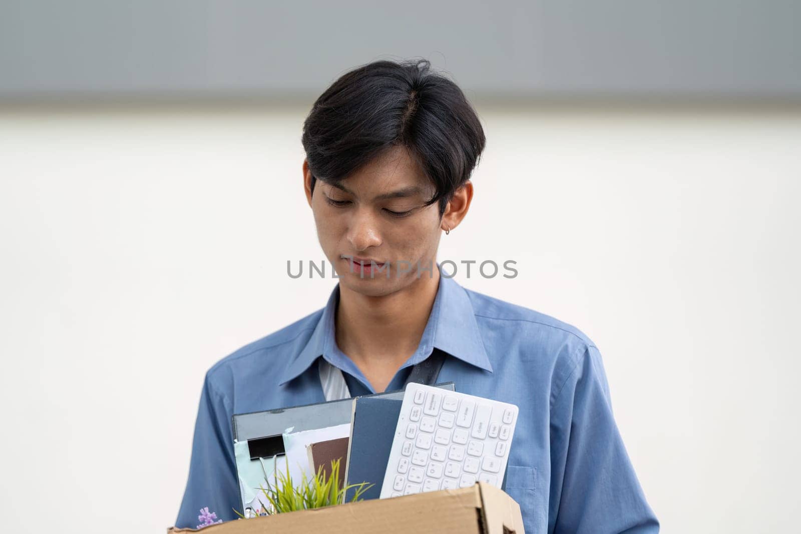An individual walks away from the office holding a box of personal items, marking the end of a job and the beginning of a new chapter.