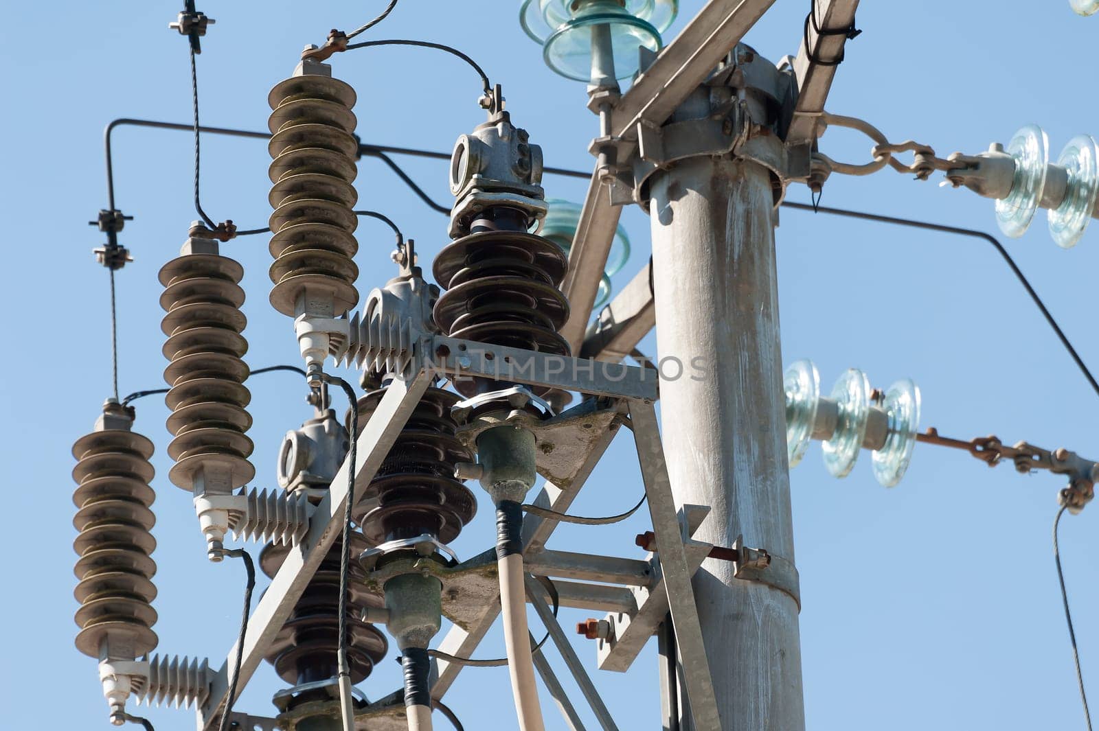 Electric pole connect to the high voltage electric wires on blue sky background.