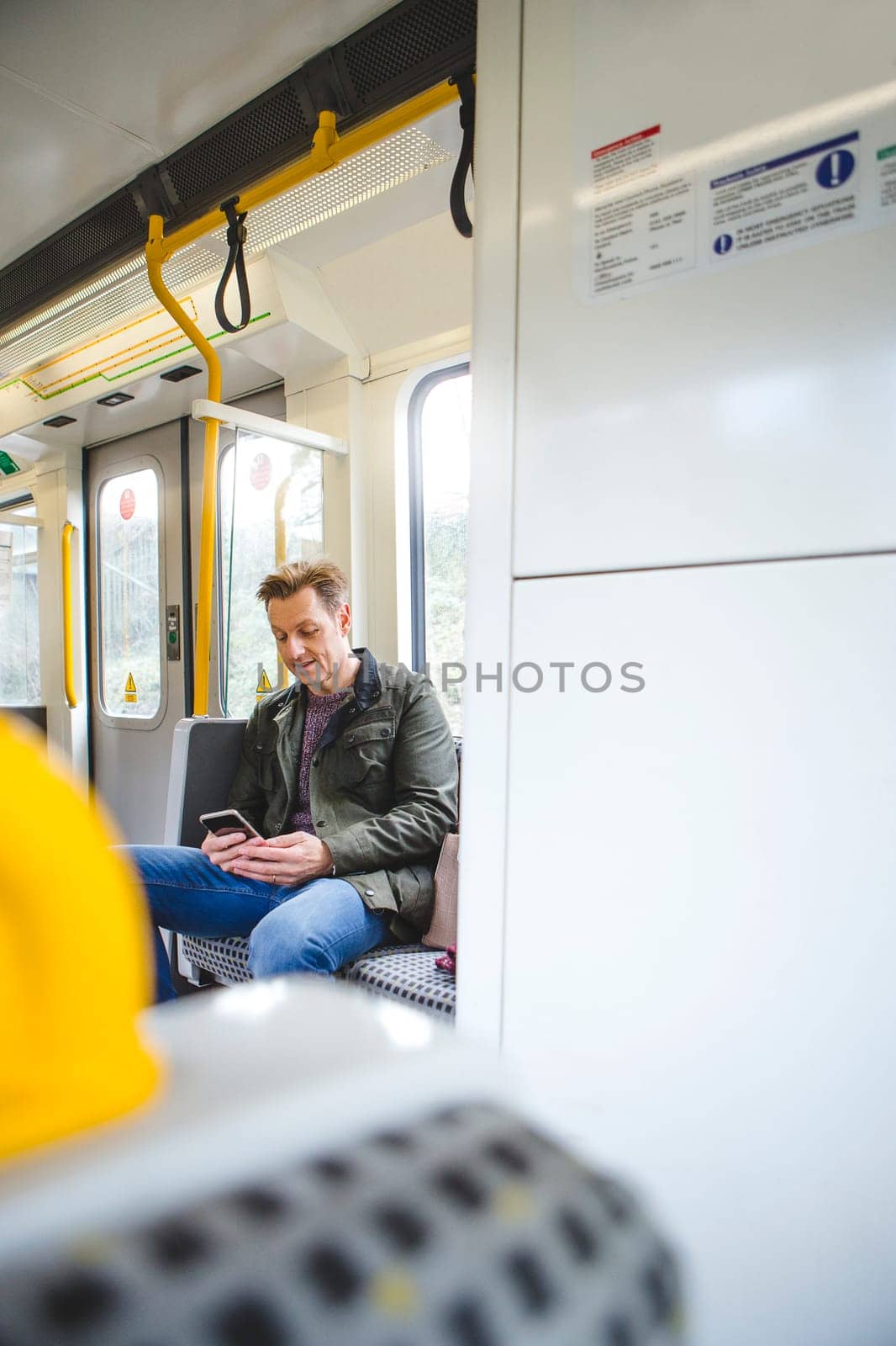 Man sitting on the train using his smart phone.