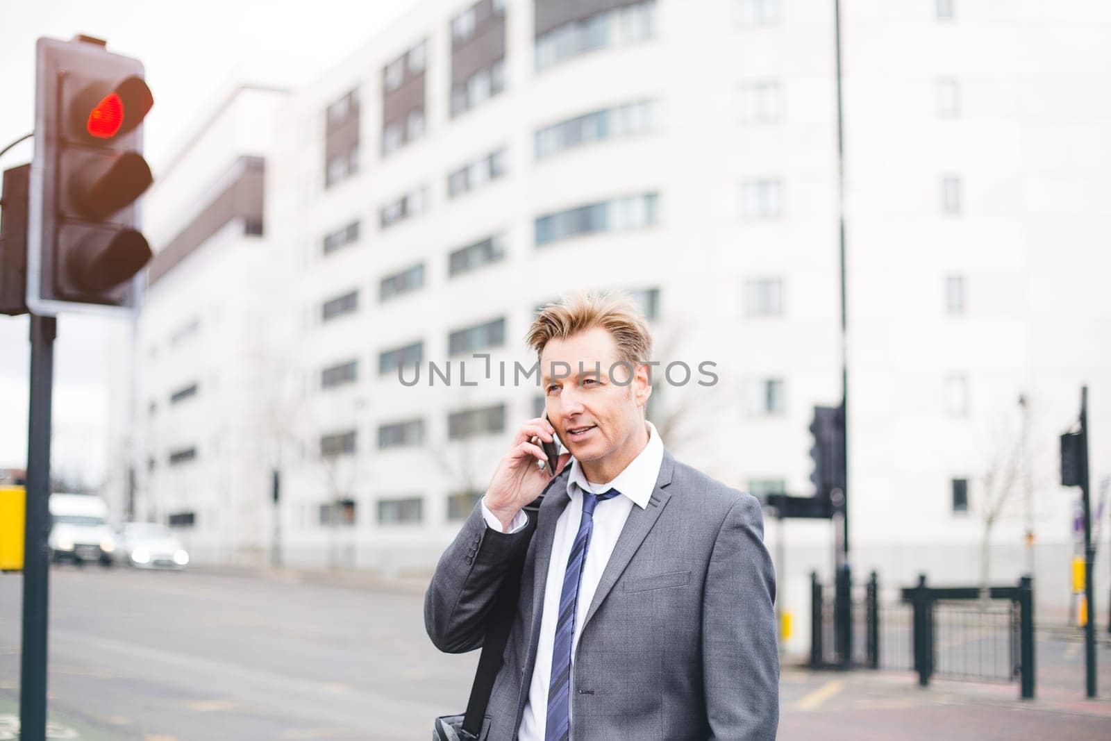 Business man in the city. He is talking on his smartphone.