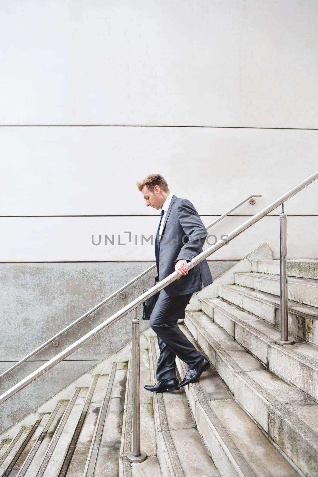 Businessman on his way to work. He is dressed in a formal suit and is walking down some steps.