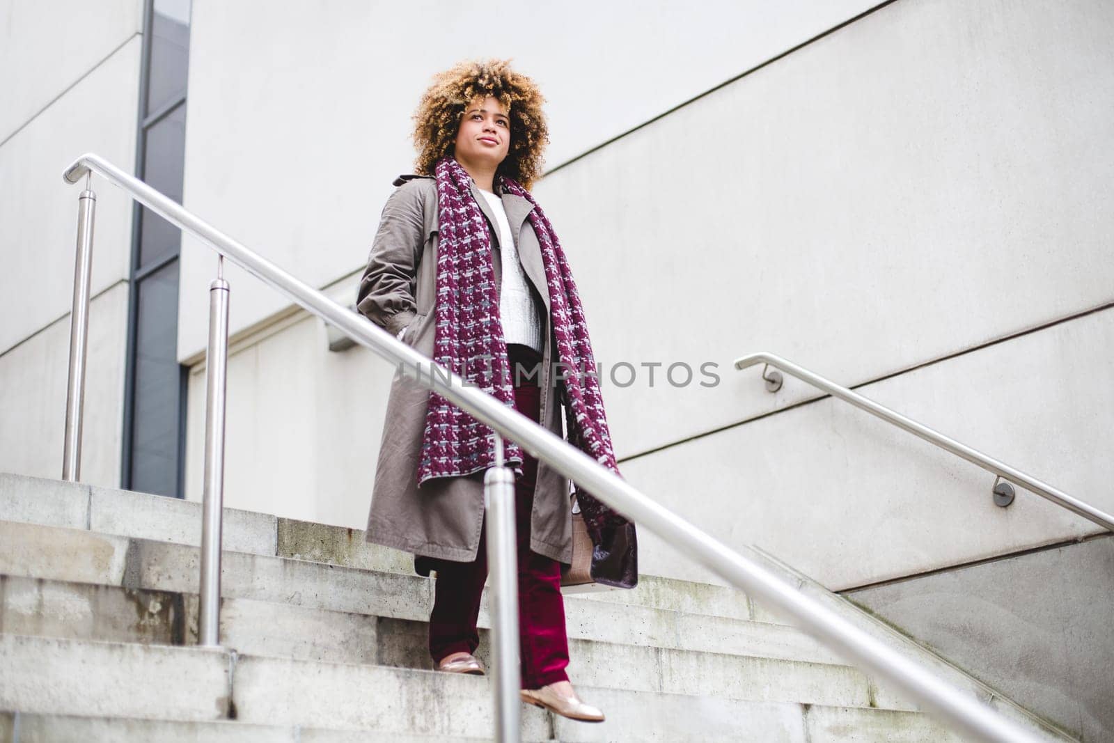 Businesswoman commuting to work in the city. She is walking down some stairs.