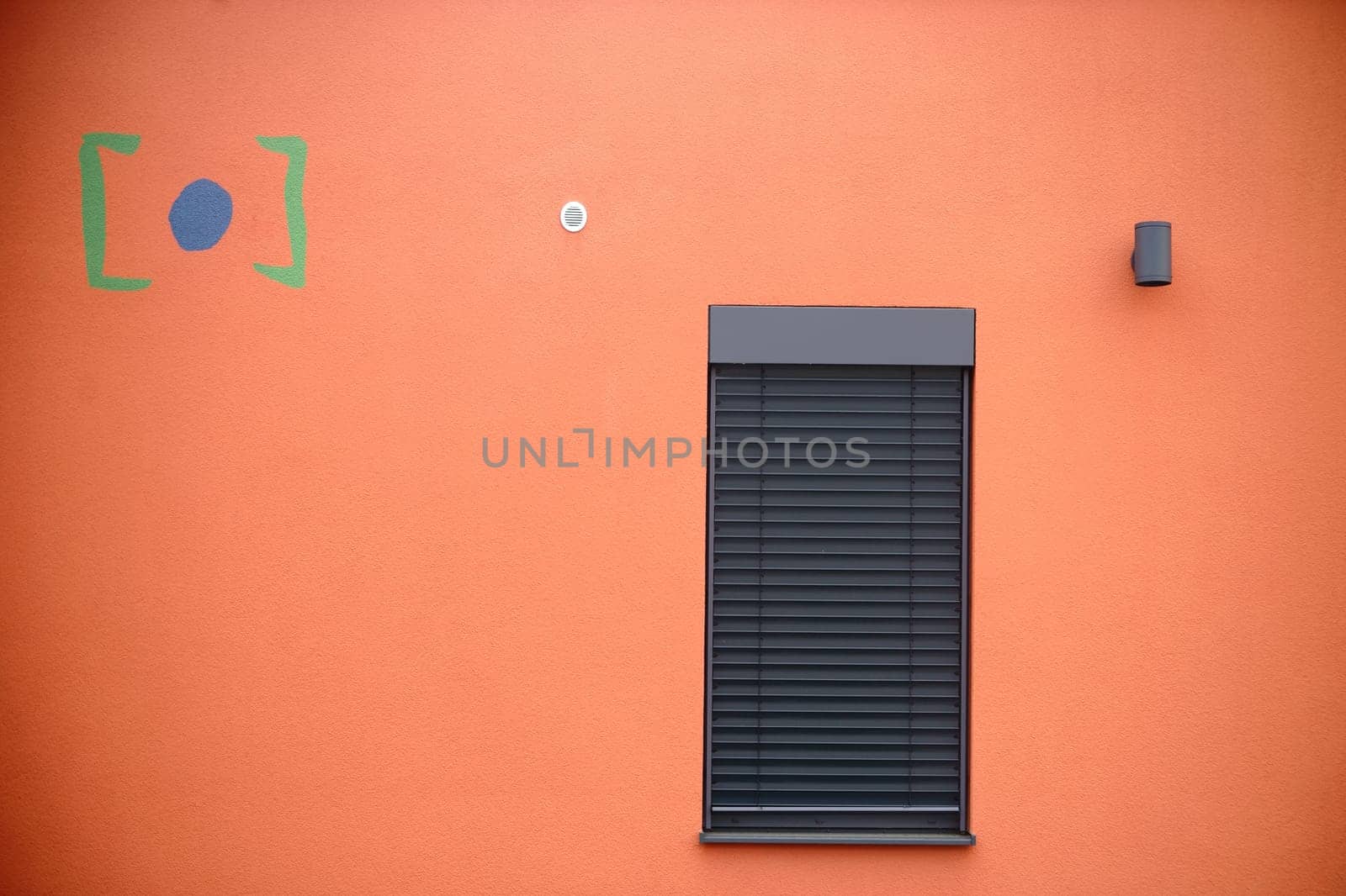 The modern façade of a modern residential building with a metal window with metal blind.