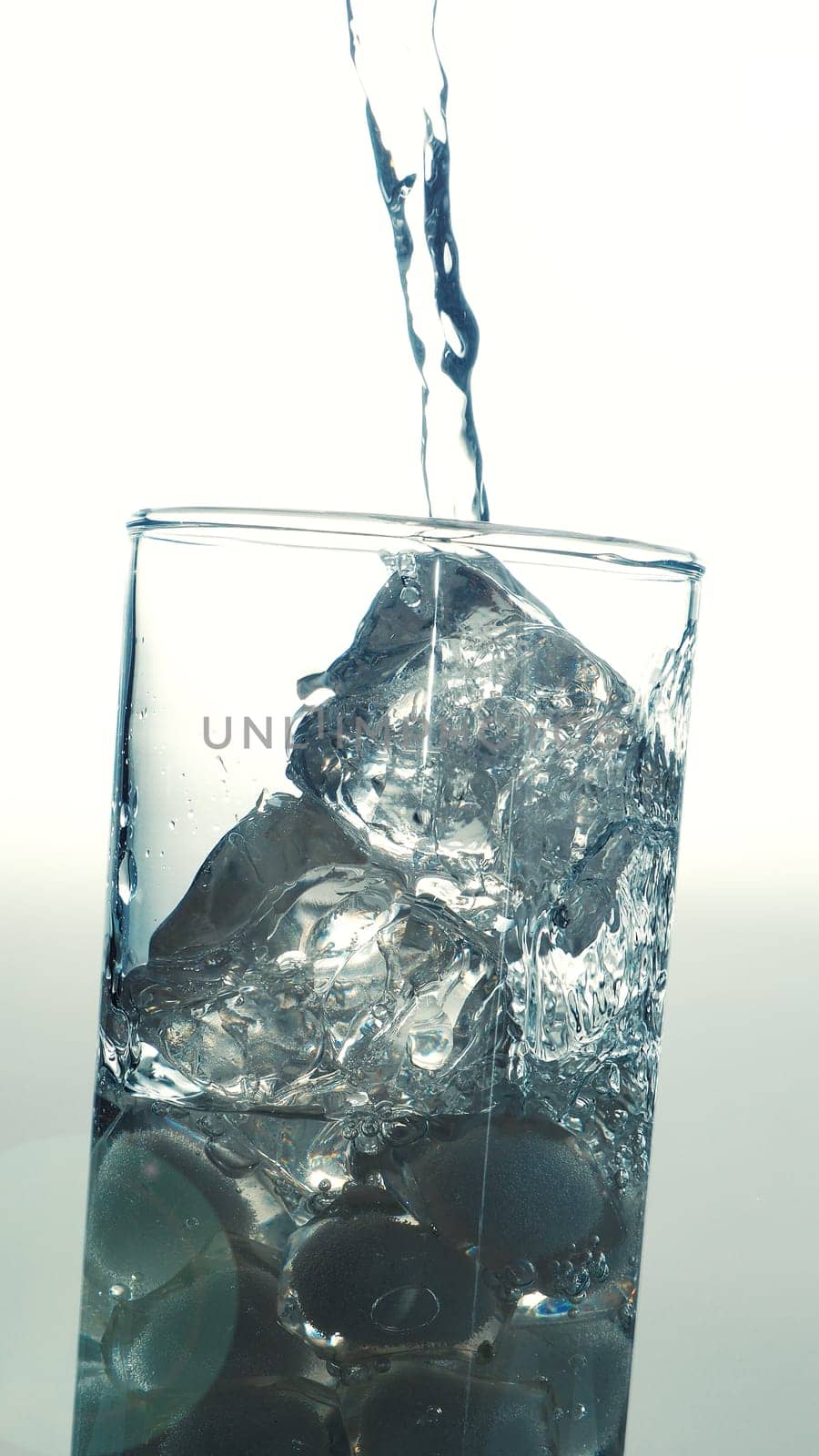 Pouring fresh table water in a glass with ice cubes, vintage film effects with lens flares