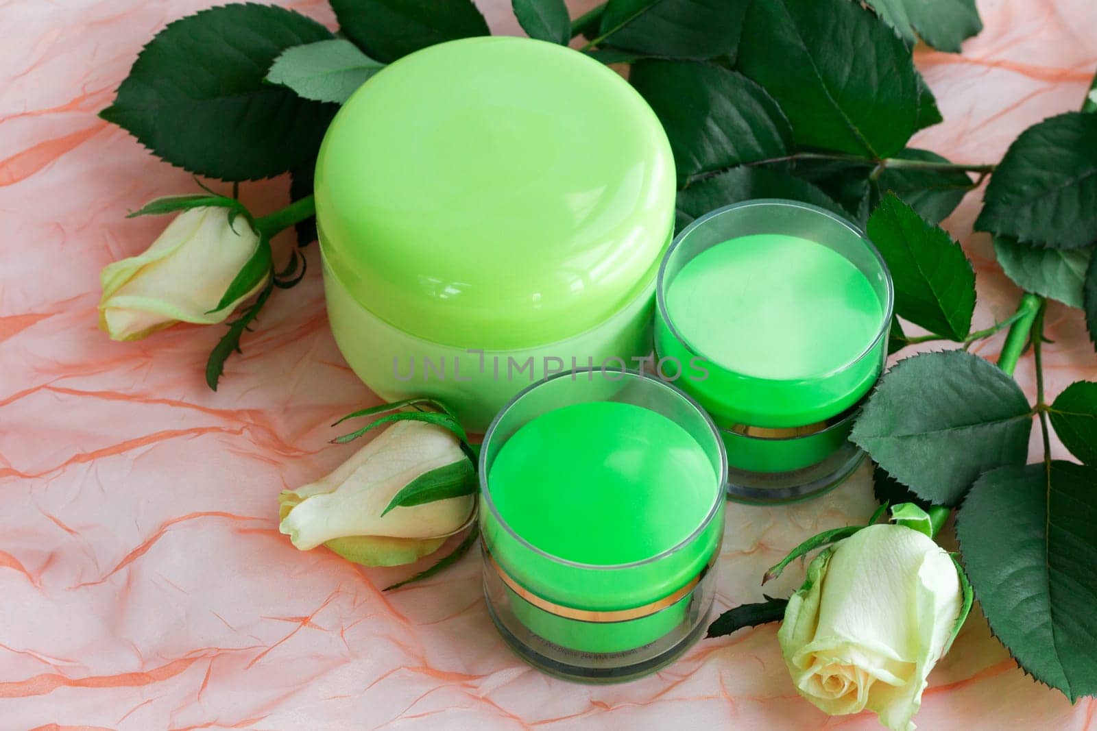 Set of three green cosmetic cream bottles with white roses